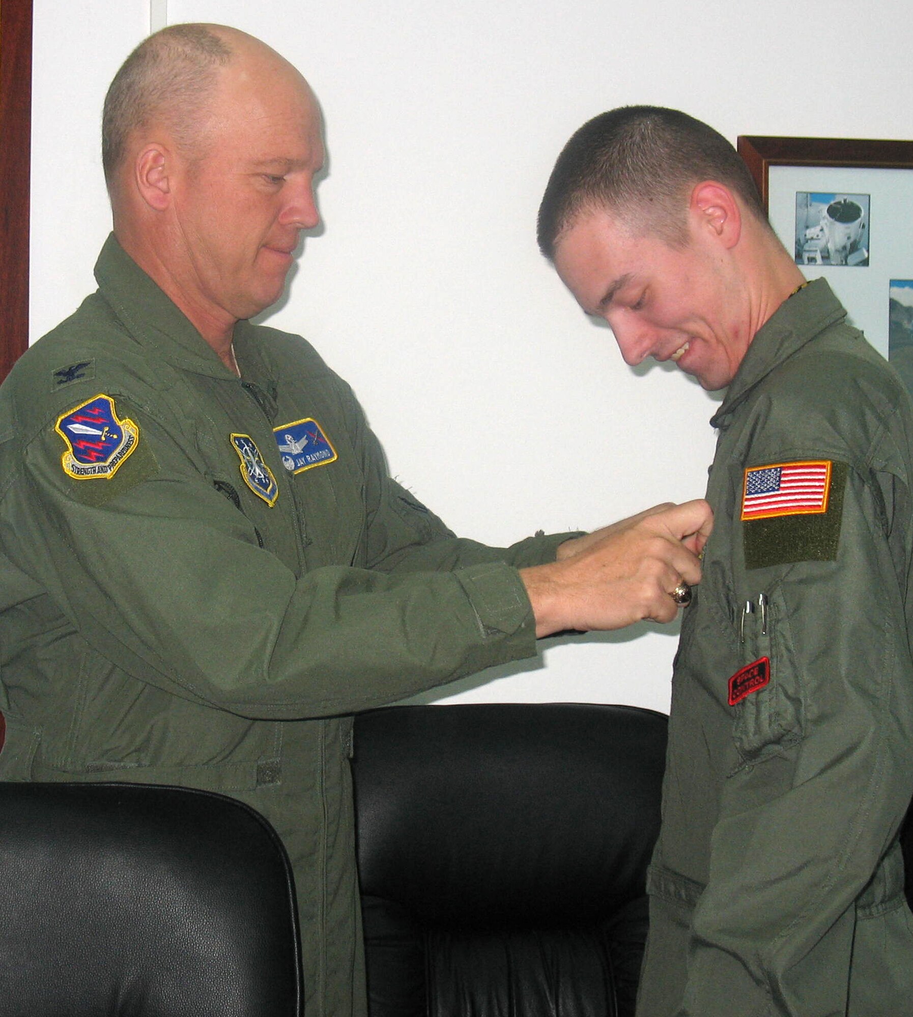 Airman 1st Class Matthew Dillon, Detachment 4, 21st Operations Group, receives his basic space specialty badge after giving Col. Jay Raymond, 21st Space Wing commander, a space professional certification briefing April 12. Colonel Raymond and Chief Master Sgt. Timothy Omdal, 21st SW command chief, visited the detachment, based at Moron Air Base, Spain, to get a first-hand look at how the unit contributes to U.S. Strategic Command’s space control mission of detecting, tracking and identifying all manmade deep-space objects. (U.S. Air Force photo/Senior Airman Karen Ness)
