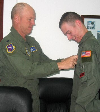 Airman 1st Class Matthew Dillon, Detachment 4, 21st Operations Group, receives his basic space specialty badge after giving Col. Jay Raymond, 21st Space Wing commander, a space professional certification briefing April 12. Colonel Raymond and Chief Master Sgt. Timothy Omdal, 21st SW command chief, visited the detachment, based at Moron Air Base, Spain, to get a first-hand look at how the unit contributes to U.S. Strategic Command’s space control mission of detecting, tracking and identifying all manmade deep-space objects. (U.S. Air Force photo/Senior Airman Karen Ness)