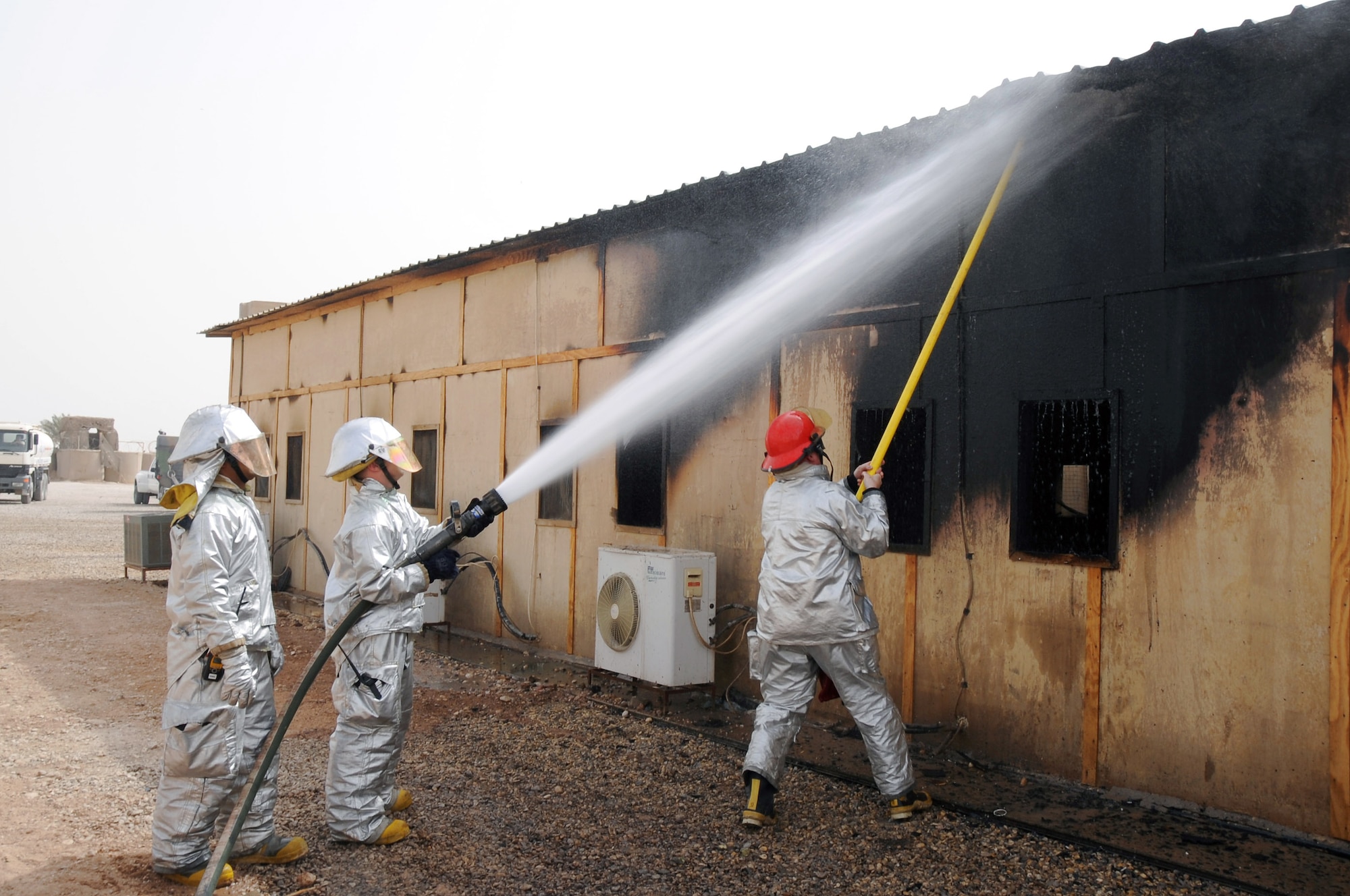 The 407th Expeditionary Civil Engineering Squadron firefighters extinguish spot fires on a building in the Romanian camp April 11 at Ali Base, Iraq. The Air Force emergency response forces respond to all emergencies here including coalition partners. The building was destroyed but there were no casualties. (U.S. Air Force photo/Tech. Sgt. Sabrina Johnson) 
