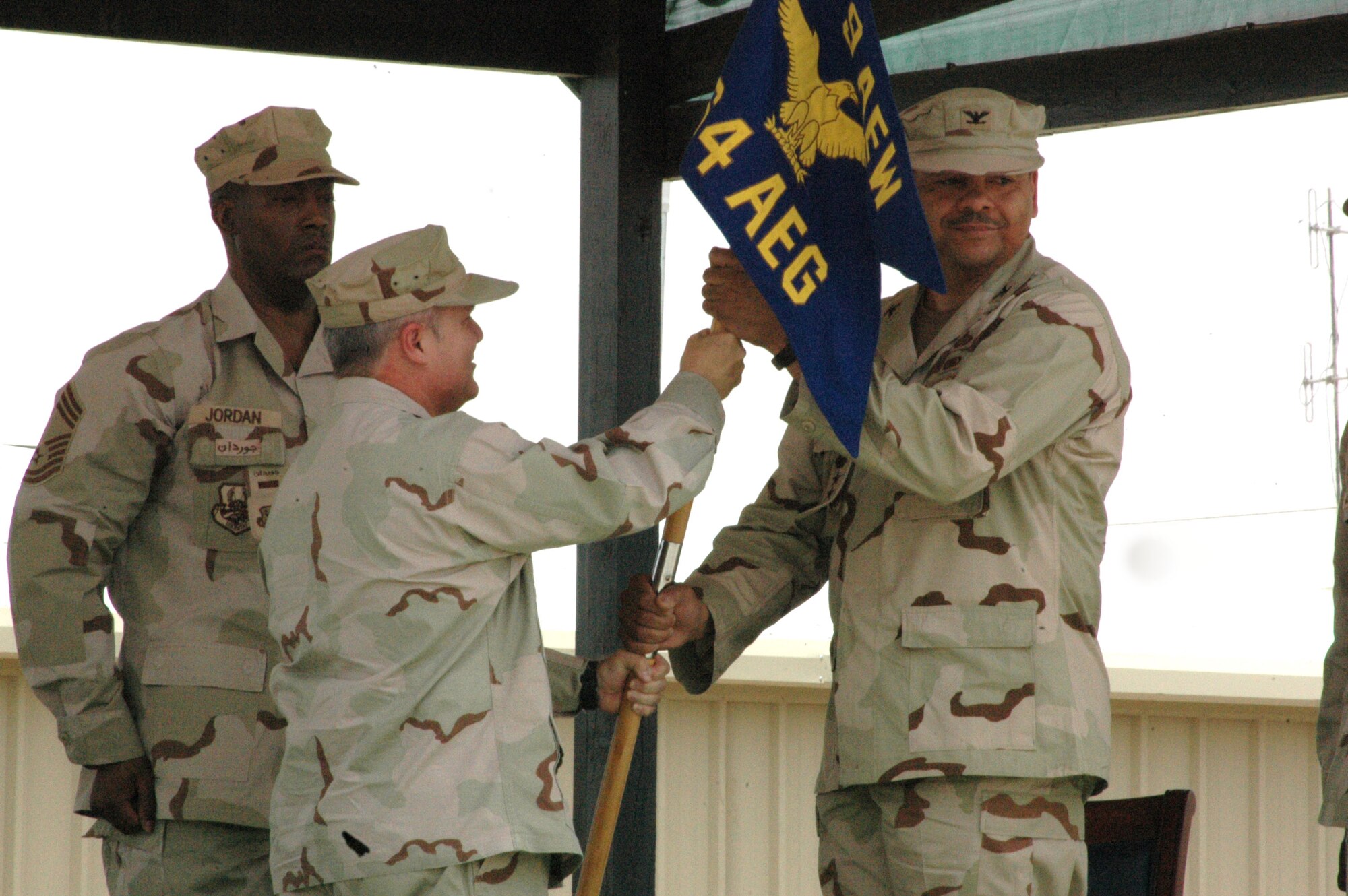 SOUTHWEST ASIA -- Brig. Gen. Charlie Lyon, 379th Air Expeditionary Wing commander, passes the 64th Air Expeditionary Group guide on to Col. Col. Willie Braggs, III, who took command of the group in a ceremony 1,500 miles from Southwest Asia's 379th AEW headquarters April 14. (U.S. Air Force photo by Senior Airman Carolyn Viss)