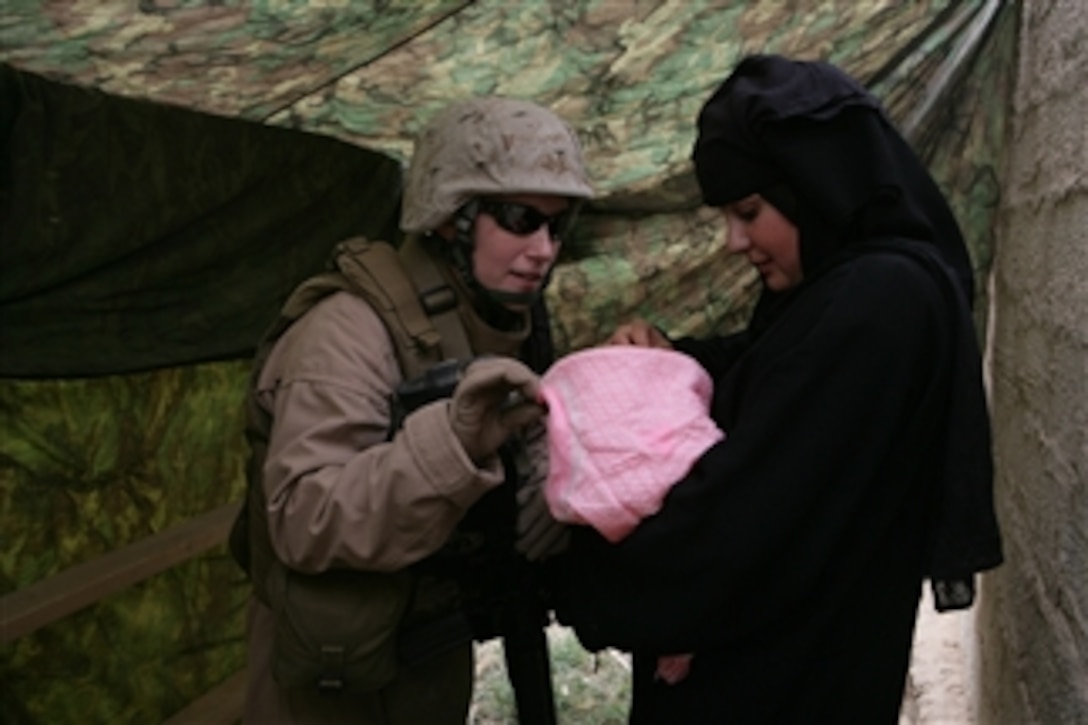 U.S. Marine Corps Cpl. Jessica Morse looks at an Iraqi woman's baby during a cooperative medical engagement in Abu Kalifa, Iraq, on April 12, 2008.  Marines assigned to 2nd Battalion, 3rd Marine Regiment and Iraqi police are providing medical care to villagers during the joint engagement.  