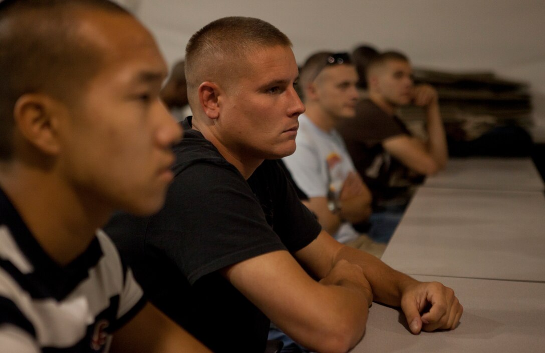 Lance Cpl. Jason Compton, Mooresville, N.C., with Communications Co., 4th Marine Logistics Group, and other Marines listen to the welcoming brief at the Joint Reception Center of Camp Wilson for exercise Javelin Thrust July 5, 2012. Javelin Thrust is an annual large-scale exercise here which allows active and reserve Marines and sailors from 38 different states to train together as a seamless Marine Air Ground Task Force.