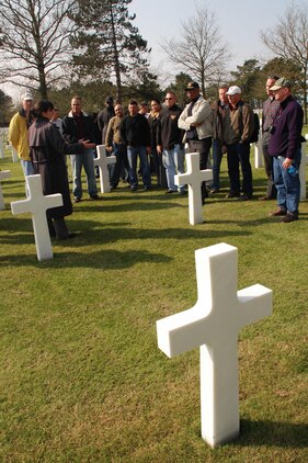 Marines from Marine Corps Forces Europe listen to a tour guide explain the story of one of the soldiers laid to rest at the Normandy American Cemetery and Memorial at Omaha Beach. The Marines' visit was part of a professional military education study of Operation Overlord, the Allied invasion of Nazi occupied France in 1944.