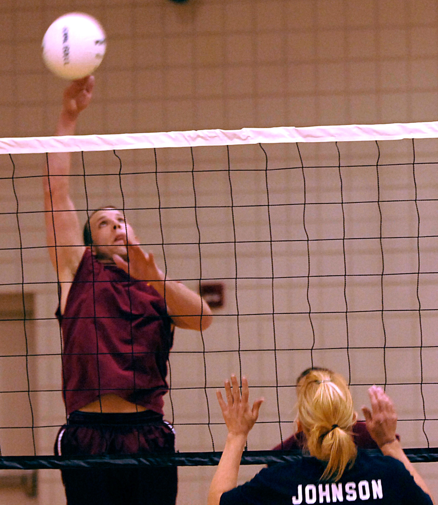 MCCONNELL AIR FORCE BASE, Kan. -- Airman Matthew McCarthy, 22nd Medical Group, glides through the air to spike the ball at Courtney Johnson, 22nd Services Squadron, at the fitness center here, April 10.  The 22nd Medical Group shut out 22nd Services Squadron 25-14, 25-14, putting the MDG record to three wins and zero losses this season.  (Photo by Staff Sgt. Ronald Lafosse.)