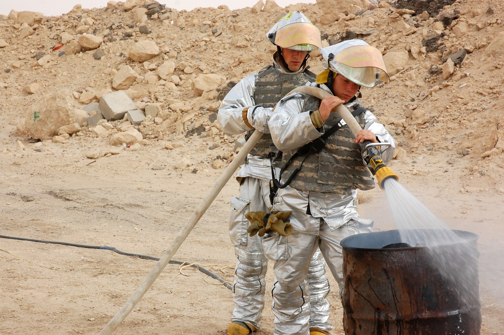 SOUTHWEST ASIA -- Senior Airman Jeffrey Sawmiller (front) and Senior Airman Corey Kostroski, 386th Expeditionary Civil Engineer Squadron fire fighters, put out a fire during a battle drill April 09, 2008, on an air base in the Persian Gulf Region. Colonel Robert Swisher, 386th Air Expeditionary Wing commander, continually tests the combat readiness and response capabilities of the Airmen in the wing. (U.S. Air Force photo/ Staff Sgt. Patrick Dixon)