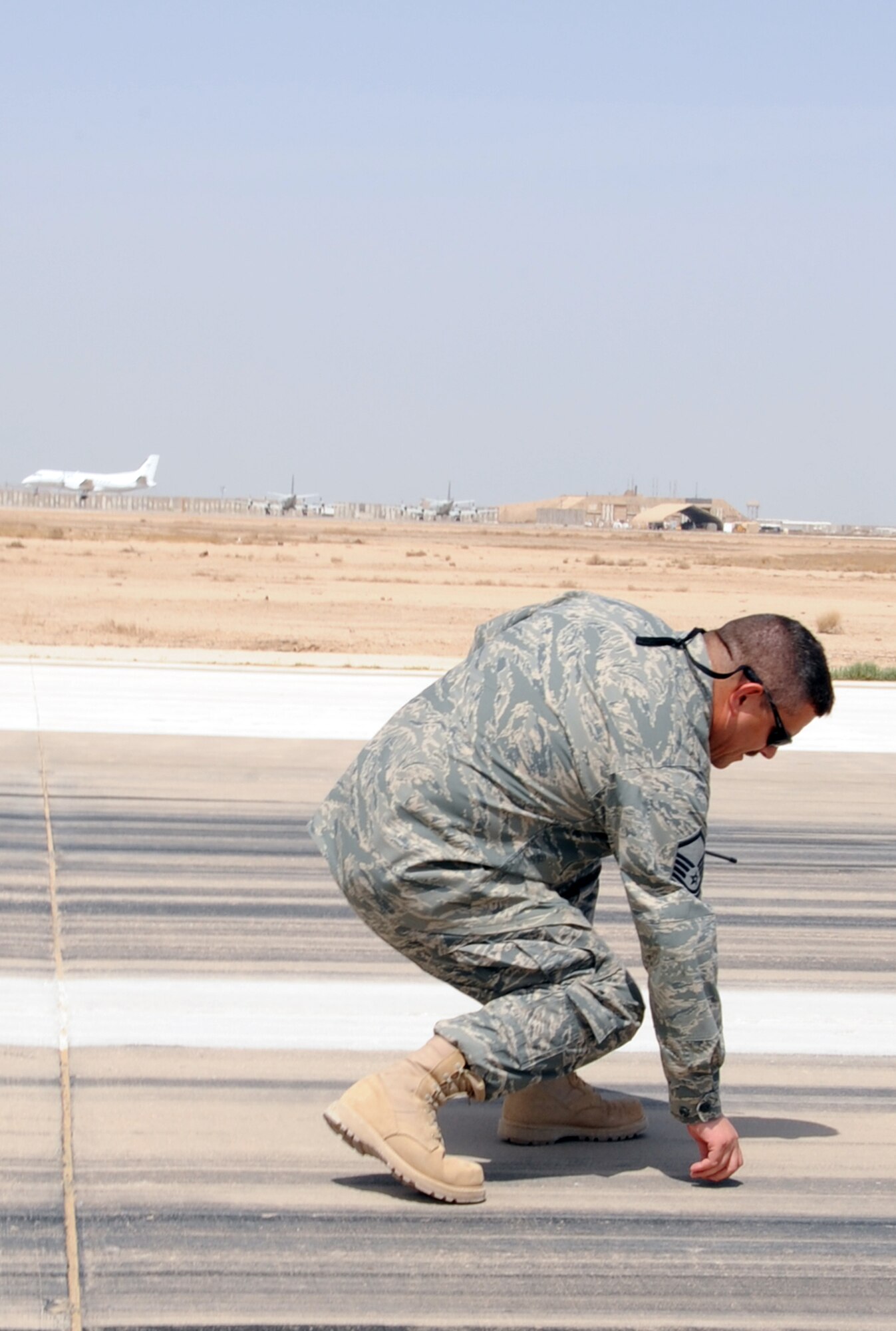 ALI BASE, Iraq -- Master Sgt. Matthew Smith, 407th Expeditionary Operations Squadron airfield manager, performs a Foreign Object Debris check immediately after the landing of a C17 here April 16.  A FOD check is performed after the landing of all heavy aircraft on Ali Base to ensure the airfield pavement remains FOD free. Sergeant Smith is deployed from McConnell AFB, Kan.  (U. S. Air Force photo / Tech. Sgt. Sabrina Johnson)
