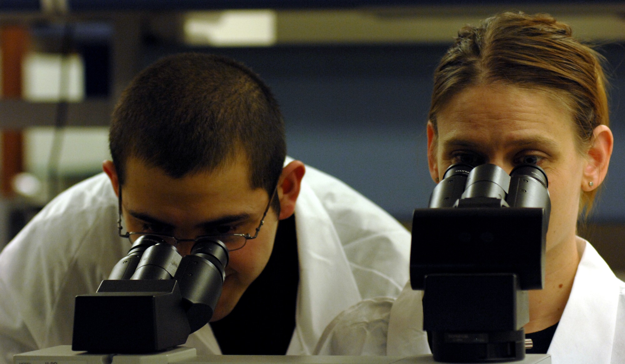AVIANO AIR BASE, Italy --  Laboratory technicians Airman 1st Class Emmanuel Garcia and Tech. Sgt. Heidi Williams look thought microscopes to count white blood cells April 15. These tests help medical personal identify problems in a patient's blood that could cause them to be sick.  (U.S. Air Force photo/Airman 1st Class Tabitha M. Mans)