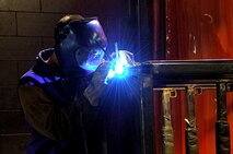 MINOT AIR FORCE BASE, N.D. -- Airman 1st Class Tom Johnson, 5th Maintenance Squadron, carefully welds a new door hinge onto a tire rack here April 9.  The welding shop takes safety seriously due to the weight of the materials that they handle and the crippling effects a welding arc can have on a person’s eye sight.  (U.S. Air Force photo by Airman 1st Class Kelly Timney)