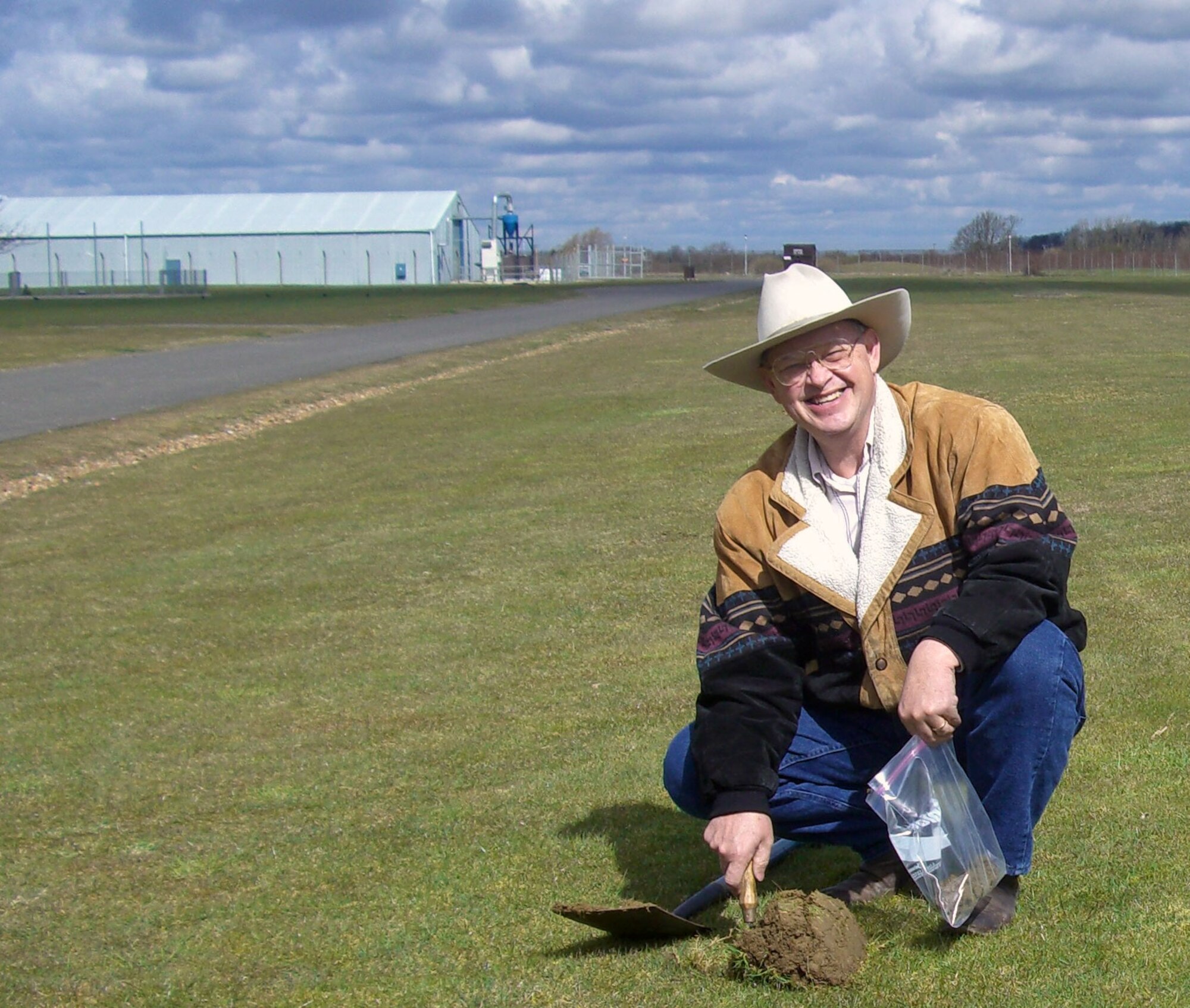 Mr. Jerry Carter digs soil from where the main runway once stood during World War II at RAF Molesworth. Mr. Carter is the son of Staff Sgt. Edward K. Carter, U. S. Army Air Corps  who served with the 359th Bomb Squadron, 303rd Bomb Group (Heavy).  His late father always wanted to return to Molesworth; but it was not to be.  The soil will be distributed on Staff Sgt. Carter's grave in the United States.  (U.S. Air Force photo by Peter Park)