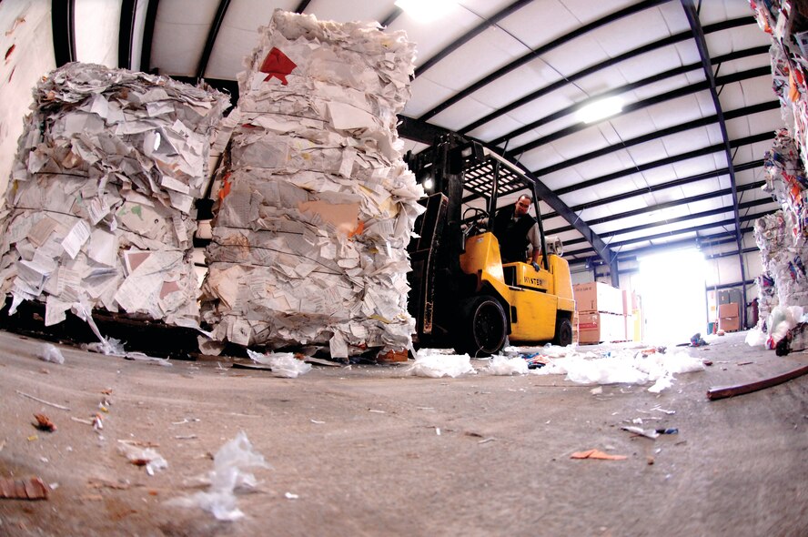 Curtis Carlisle, working in the Recycling center warehouse, prepares to load bales of mixed paper onto a trailer for transport to a local vendor. (U.S. Air Force photo/Abner Guzman)