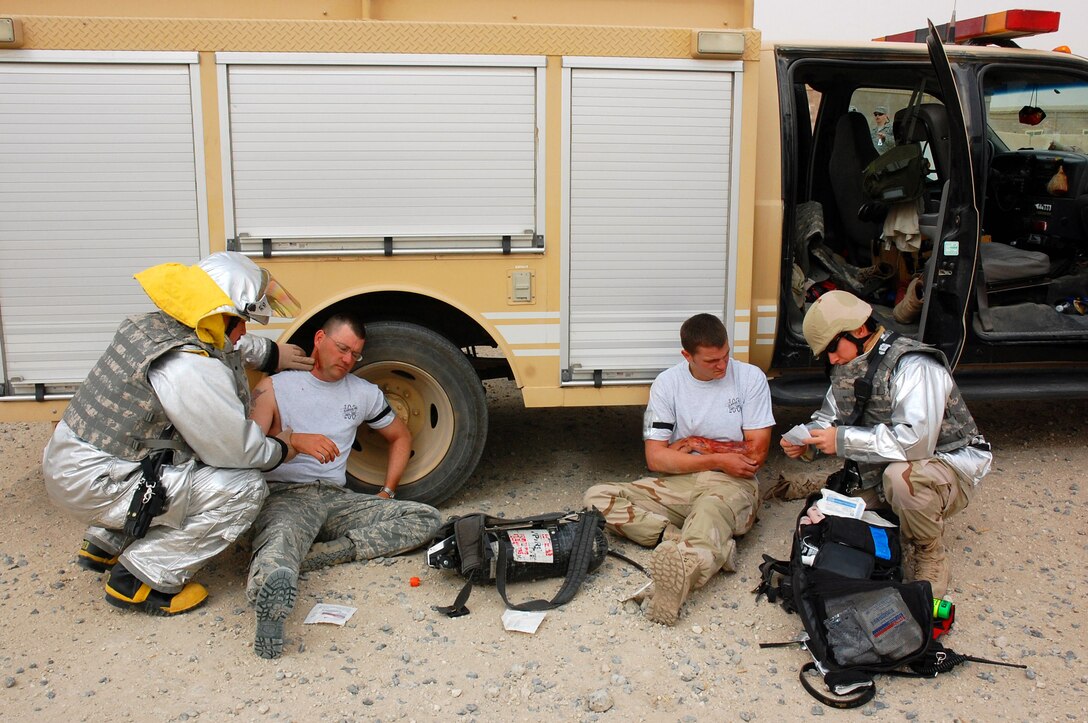 Staff Sgt. Michael Crispin (left) and Senior Airman Jeremy Brush (far right) administer first aid to Airmen with simulated wounds during a battle drill April 9 at a Southwest Asian air base. Base members continually test the combat readiness and response capabilities of the Airmen in the wing. Sergeant Crispin and Airman Brush are 386th Expeditionary Civil Engineer Squadron firefighters. (U.S. Air Force photo/Staff Sgt. Patrick Dixon) 
