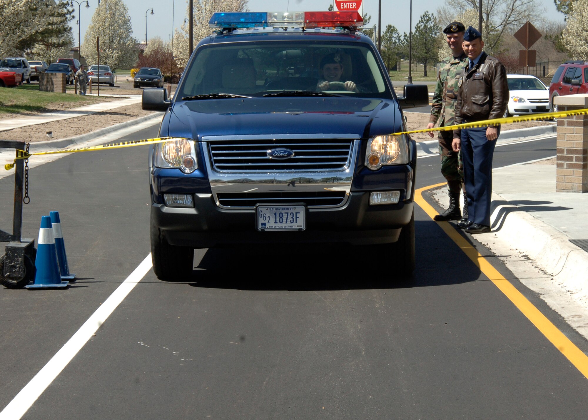 MCCONNELL AIR FORCE BASE, Kan. -- Senior Airman Jennifer Konrad, Security Forces Squadron, drives Maj. Michael Green’s government vehicle through a caution tape ribbon to signify the official re-opening of McConnell Air Force Base’s front housing gate, April 15. Col. James Vechery, 22nd Air Refueling Wing commander and Maj. Michael Green, 22nd Security Forces Squadron commander, checked Airman Konrad’s ID before she drove through the ribbon. (Photo by Airman Justin Shelton)
