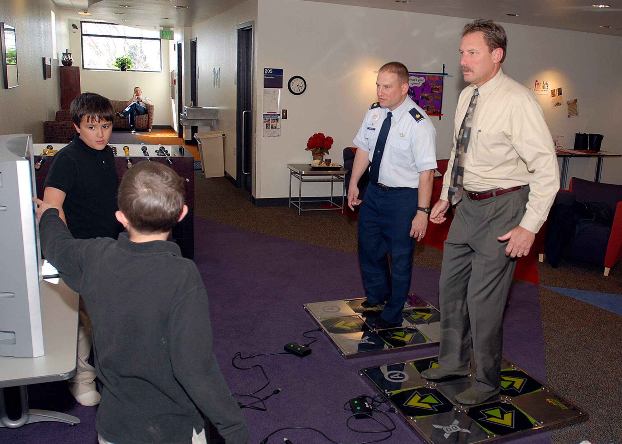 Maj. Mike Marvich, 21st Services Squadron commander, and Dan Schofield, 21st SVS deputy commander, try out the R.P. Lee Youth Center's 'Dance Dance Revolution' gaming system as Peterson youth look on April 8. The team inspected the 21st Services Squadron April 7-11 at this Colorado base to see if they qualified as the “best of the best” of services squadrons throughout the Air Force. (U.S. Air Force photo/Robert Lingley)