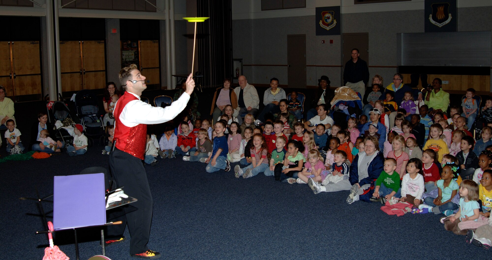 MCCONNELL AIR FORCE BASE, Kan. –Dennis Porter, entertainer, from Happy Faces Entertainment, balances a plate while entertaining a crowd of Team McConnell children look at the Robert J Dole Center Ball room, during the base library open house, April 15. (Photo by Airman Justin Shelton)