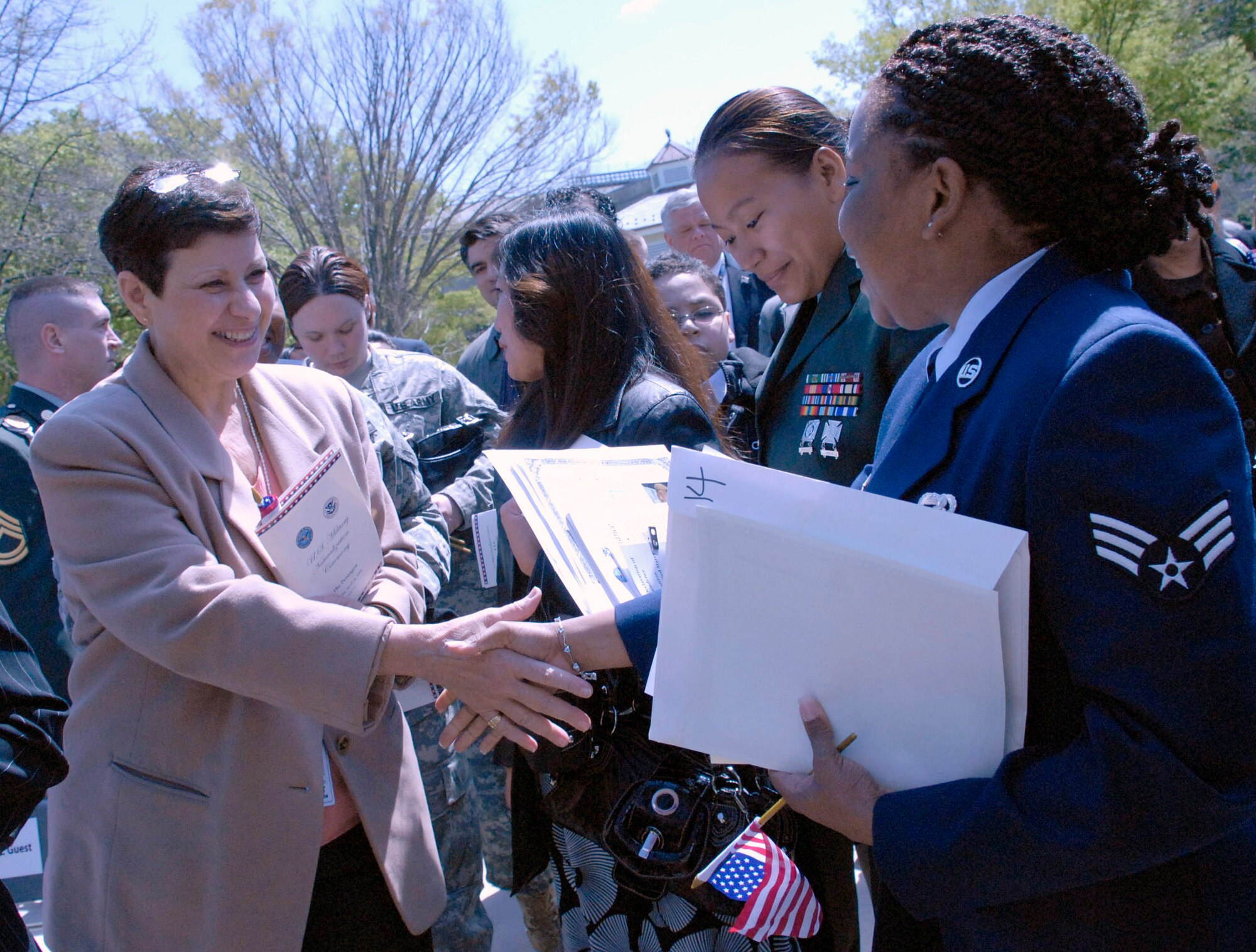 Senior Airman Cassandra Obermuller Brandon (right) accepts congratulations from audience members after accepting her naturalization certificate during a naturalization ceremony April 14 in the Pentagon's center courtyard. More than 20 servicemembers became American citizens during the ceremony. Airman Brandon, who was born and raised in Guyana, moved to the United States with her father in 1991 and joined the Air Force Reserve in 2002. (U.S. Air Force photo/Staff Sgt. Julie Weckerlein)
