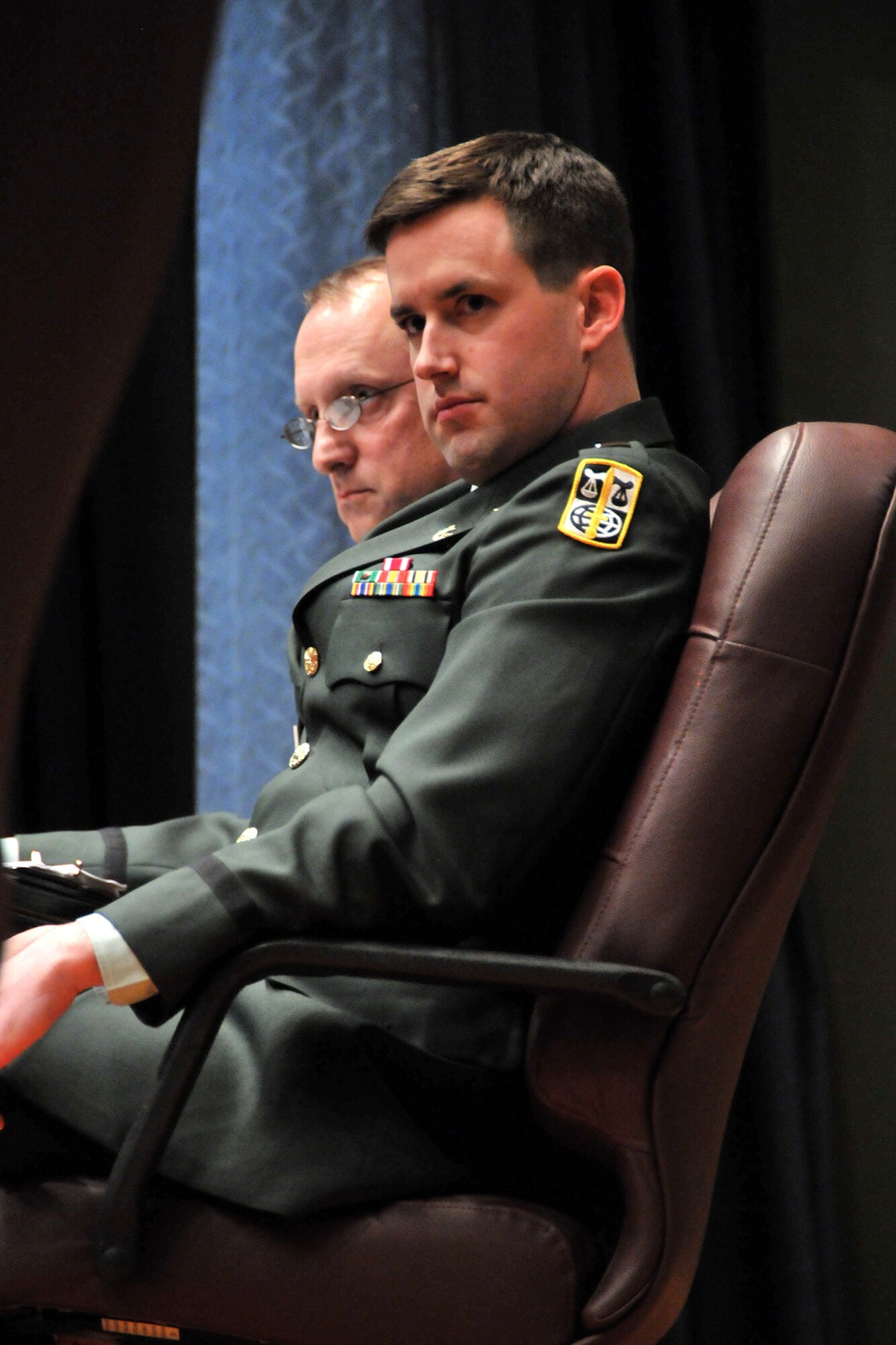 Army Capt. Michael Pond, the appellate government counsel, listened to statements made by Army Capt. Christopher Dempsey, who was arguing on behalf of Private Wilcox during the United States Court of Appeals for the Armed Forces "Project Outreach” hearing. The hearing was held at the base auditorium here April 10. (U.S. Air Force photo/John Turner)