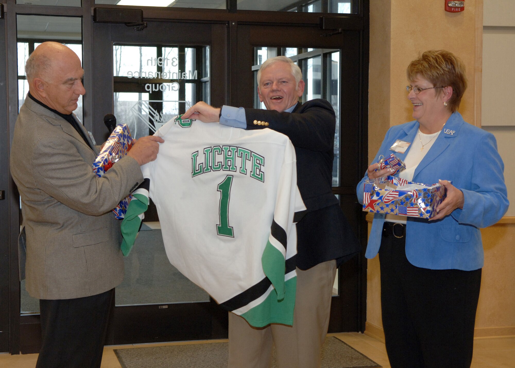 GRAND FORKS AIR FORCE BASE, N.D. - Gen. Arthur Lichte, Air Mobility Command commander (middle), is presented with a personalized Fighting Sioux jersey from John Marshall, 319 Air Refueling Wing honorary commander emeritus and Ambassador number 2, at Heritage Hall April 9. General Lichte and his wife Chris attended the event which was an evening social between wing leadership, community ambassadors, and honorary commanders. (U.S. Air Force photo by Senior Airman Tiffany Colburn). 

