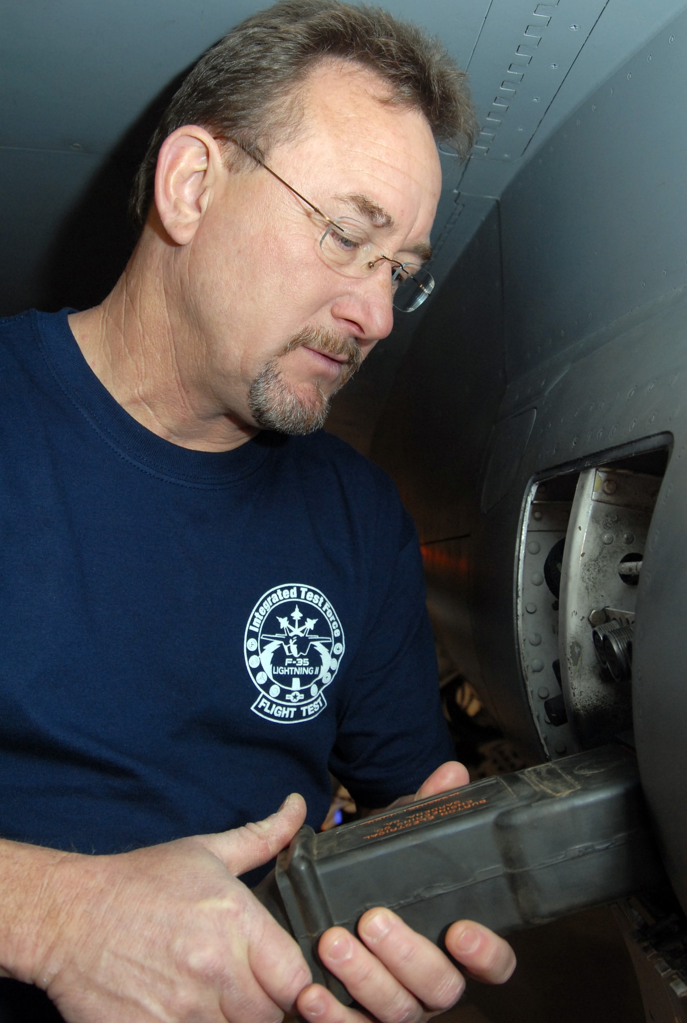 Steve Bridgers, lead facility engineer, installs a power receptacle to an aircraft during power and cooling air system training in hangar 1820 here April 15. Maintainers from the 412th Aircraft Maintenance Squadron performed the training in preparation for the F-35's tentative arrival in May. (Air Force photo by Senior Airman Julius Delos Reyes)