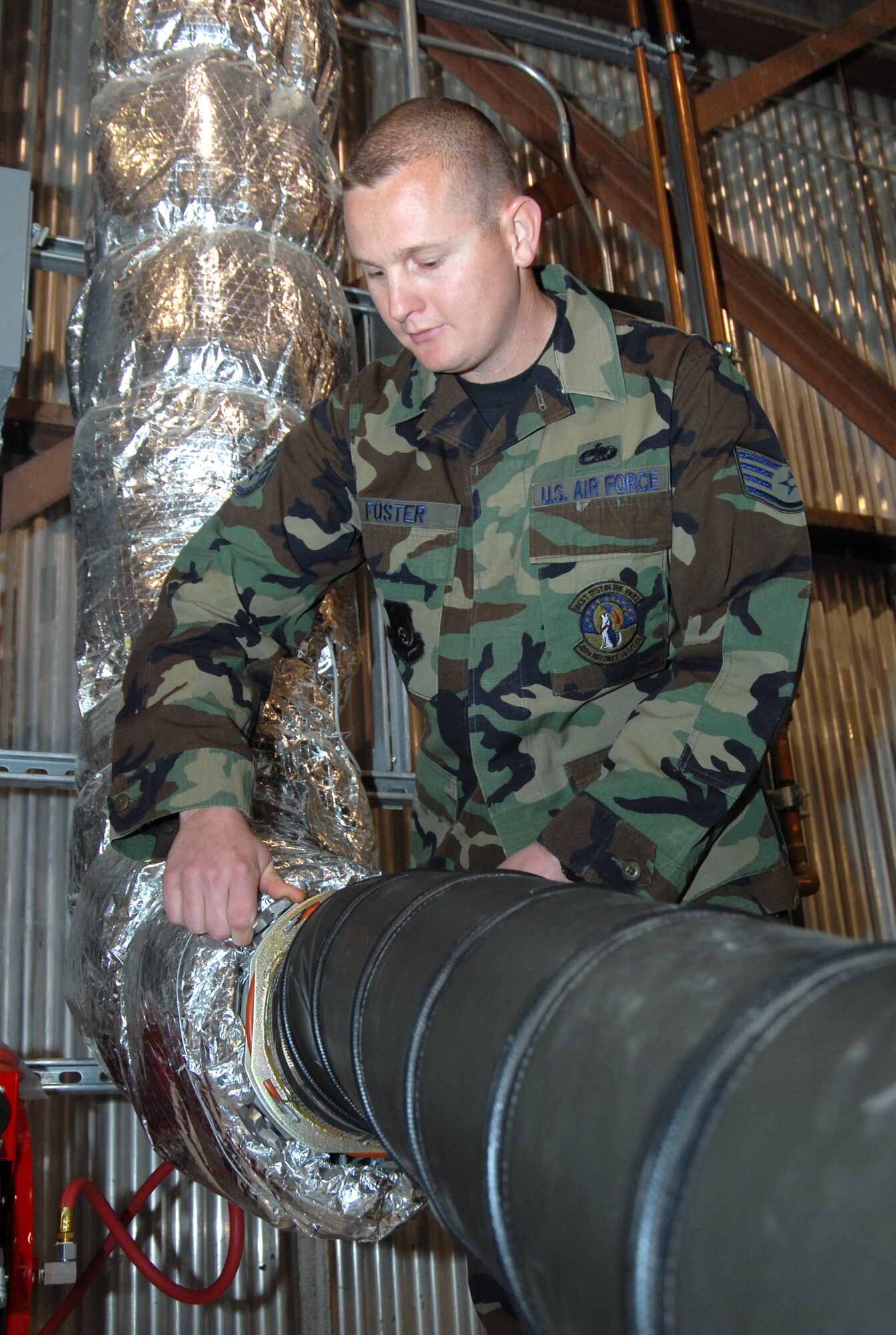 Staff Sgt. Scott Foster, 412th Aircraft Maintenance Squadron F-35 Lightning II-dedicated crew chief, completes a pre-inspection of the clamp for the air cooling duct during power and cooling air system training in hangar 1820 here April 15. Maintainers from the 412th Aircraft Maintenance Squadron performed the training in preparation for the F-35's tentative arrival in May. (Air Force photo by Senior Airman Julius Delos Reyes)