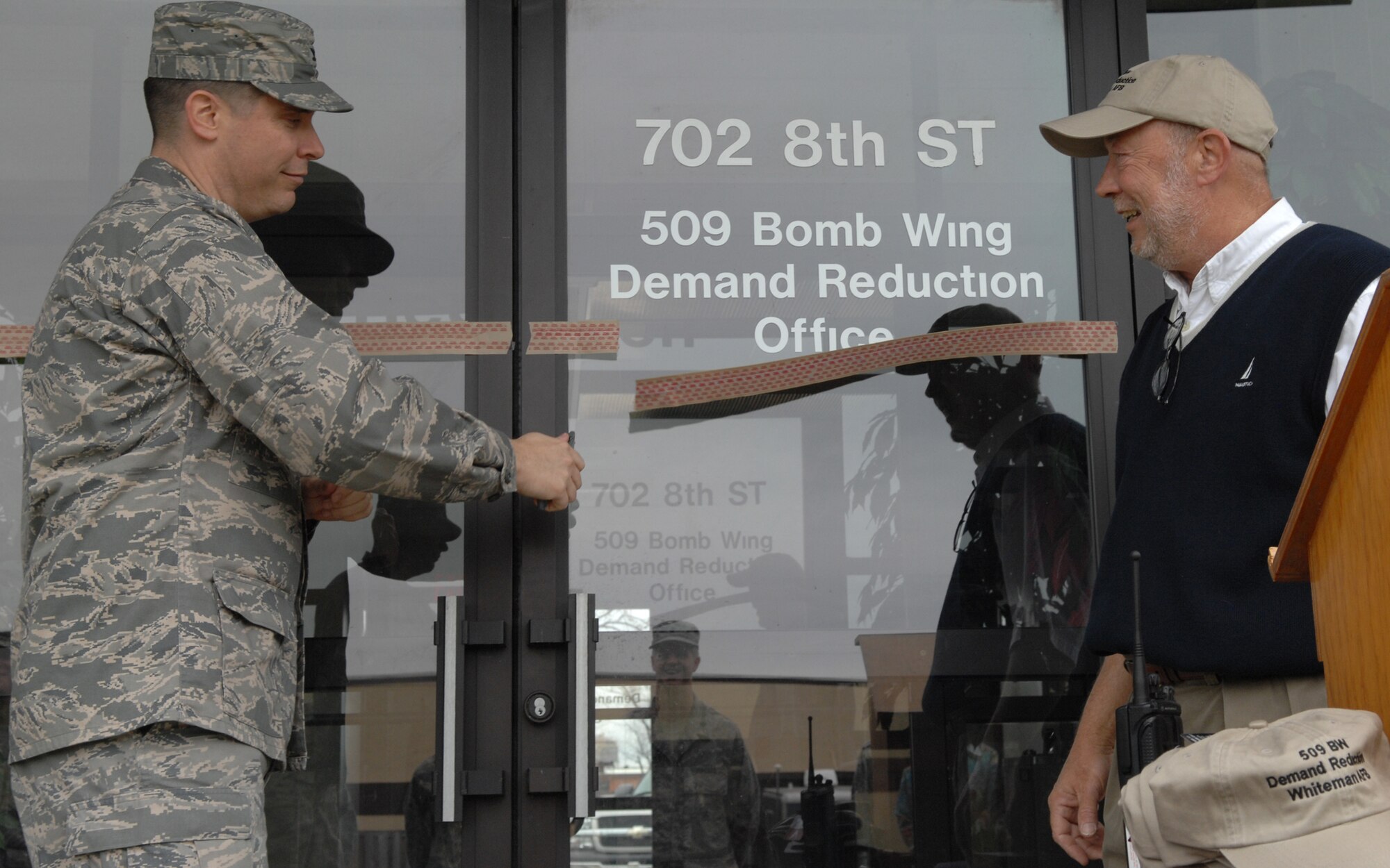 WHITEMAN AIR FORCE BASE, Mo. - Col. John Robinson, 509th Bomb Wing vice commander, cuts a ribbon as James Taylor, Whiteman's demand reduction program manager, looks on during a ribbon cutting ceremony for demand reduction’s new facility April 9. The DRP’s purpose is to maintain the health and wellness of a fit and ready fighting force; this is accomplished through comprehensive programs of education, prevention, deterrence and community outreach, according to Air Force Instruction 44-159, DRP. (U.S. Air Force photo/Airman 1st Class Stephen Linch)