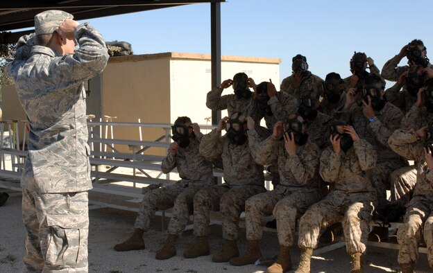 DYESS AIR FORCE BASE, Texas- Airman First Class Mathew Moklar, emergency management, demonstrates the order of tightening the gas mask to a group of marines, April 12. The order of tightening the straps is important to ensure a proper seal from chemical agents. (U.S. Air Force photo by Senior Airman Courtney Richardson)