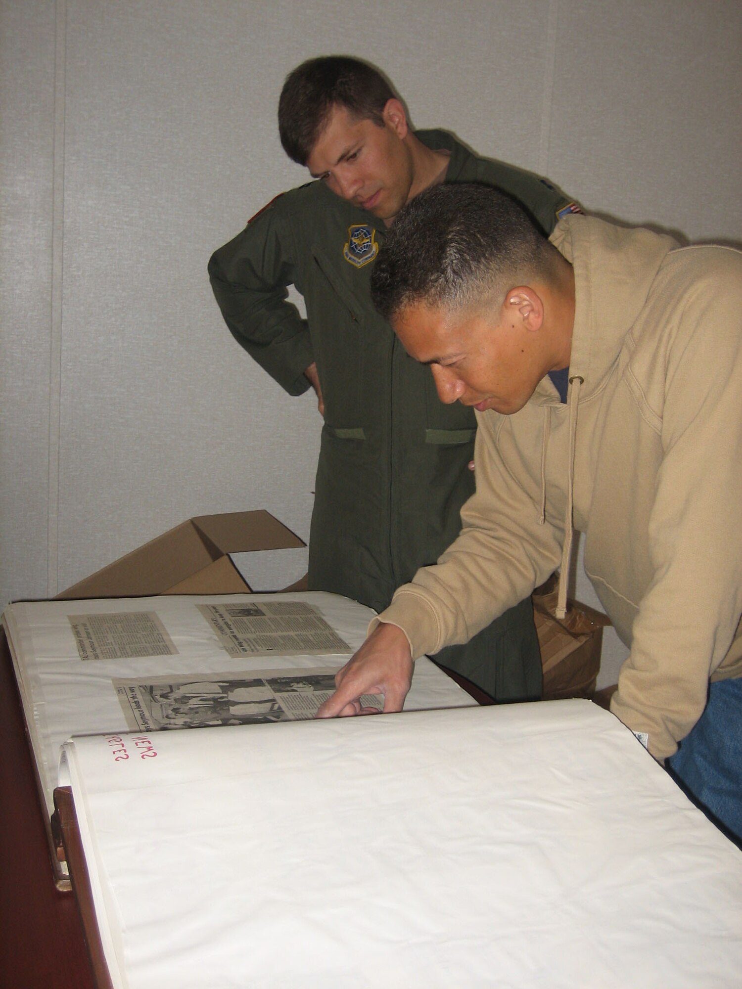 SEYMOUR JOHNSON AIR FORCE BASE, N.C. -- Lt. Col. Art Primas (front) and Capt. Chris Vecchione look at memorabilia from when the 911th Air Refueling Squadron started at Seymour Johnson Air Force Base in 1958. The book includes photos, programs, news clippings and even an autograph from Chuck Yeager. Colonel Primas is the operations officer for the 911th and Capt. Vecchione is a pilot.