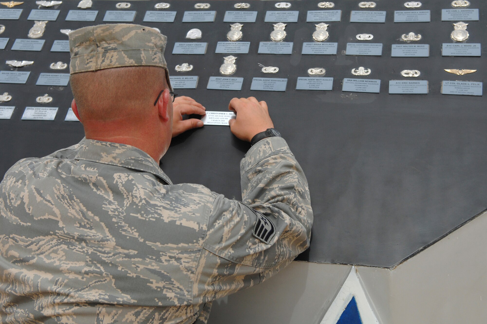 BALAD AIR BASE, Iraq -- Staff Sgt. Karl Ferree, a structural craftsman assigned to the 332nd Expeditionary Civil Engineer Squadron, positions plaques listing the names of Tech. Sgt. Anthony Capra and Staff Sgts. Christopher Frost and Travis Griffin here, April 16.  The three Airmen lost their lives during operations in Iraq during the past six weeks. The names and badges of Airmen who have died during the Global War on Terrorism are displayed on the Airman Memorial at Balad AB to serve as a reminder of those who have paid the ultimate price for America's freedom and security. Sergeant Ferree is deployed from Luke Air Force Base, Ariz. (U.S. Air Force photo/ Senior Airman Julianne Showalter)