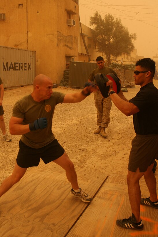 Staff Sgt. Richard A. Gonzalez, team chief, holds the punching pads as Cpl. Brendan A. Ryan, a civil affairs Marine, practices punching during a sandstorm in Hit, Iraq, May 6. Both Marines are assigned to Civil Affairs Team 3, Detachment 1, 2nd Battalion, 11th Marine Regiment, Regimental Combat Team 5. Some of the Marines with CA Team 3 are using their deployment as a way to get into the best shape they can and are posting photographs of their improvements on a Web site so their families can see their progress.