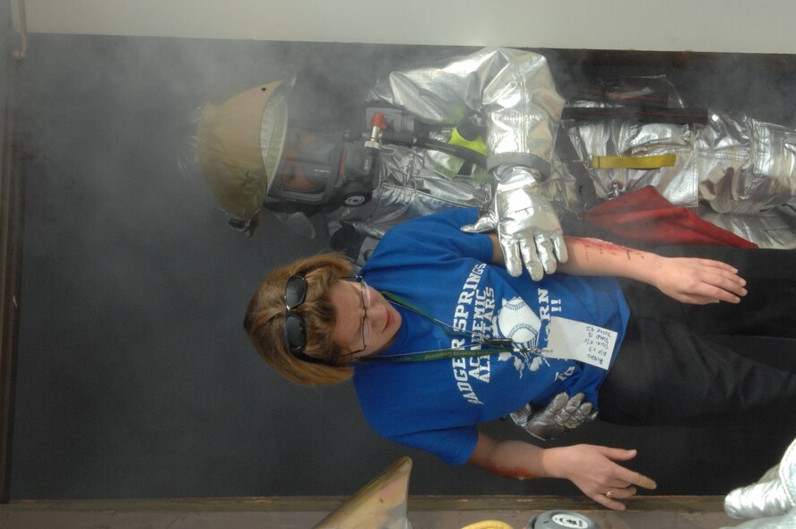 A firefighter helps a victim out of a simulated burning building.  Some one hundred disaster responders and injured actors participated in a mass casualty exercise held on the flight line at the base. Several local hospitals also participated in the exercise held at March Air Reserve Base, California. An emergency medical crew from Mercy Air airlifted simulated casualties. The exercise involved several community partners, such as Riverside EMS, AMR and Mission ambulance. (U.S. Air Force photo by 4th CTCS)