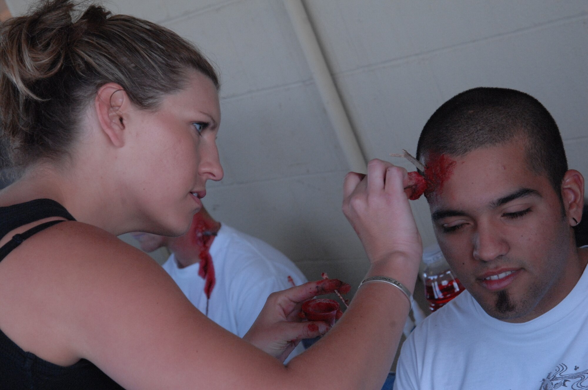 Moulage make-up artists apply blood and shrapnel to an injured actor.  Some one hundred disaster responders and injured actors participated in a mass casualty exercise held on the flight line at the base. Several local hospitals also participated in the exercise held at March Air Reserve Base, California. An emergency medical crew from Mercy Air airlifted simulated casualties. The exercise involved several community partners, such as Riverside EMS, AMR and Mission ambulance. (U.S. Air Force photo by 4th CTCS)