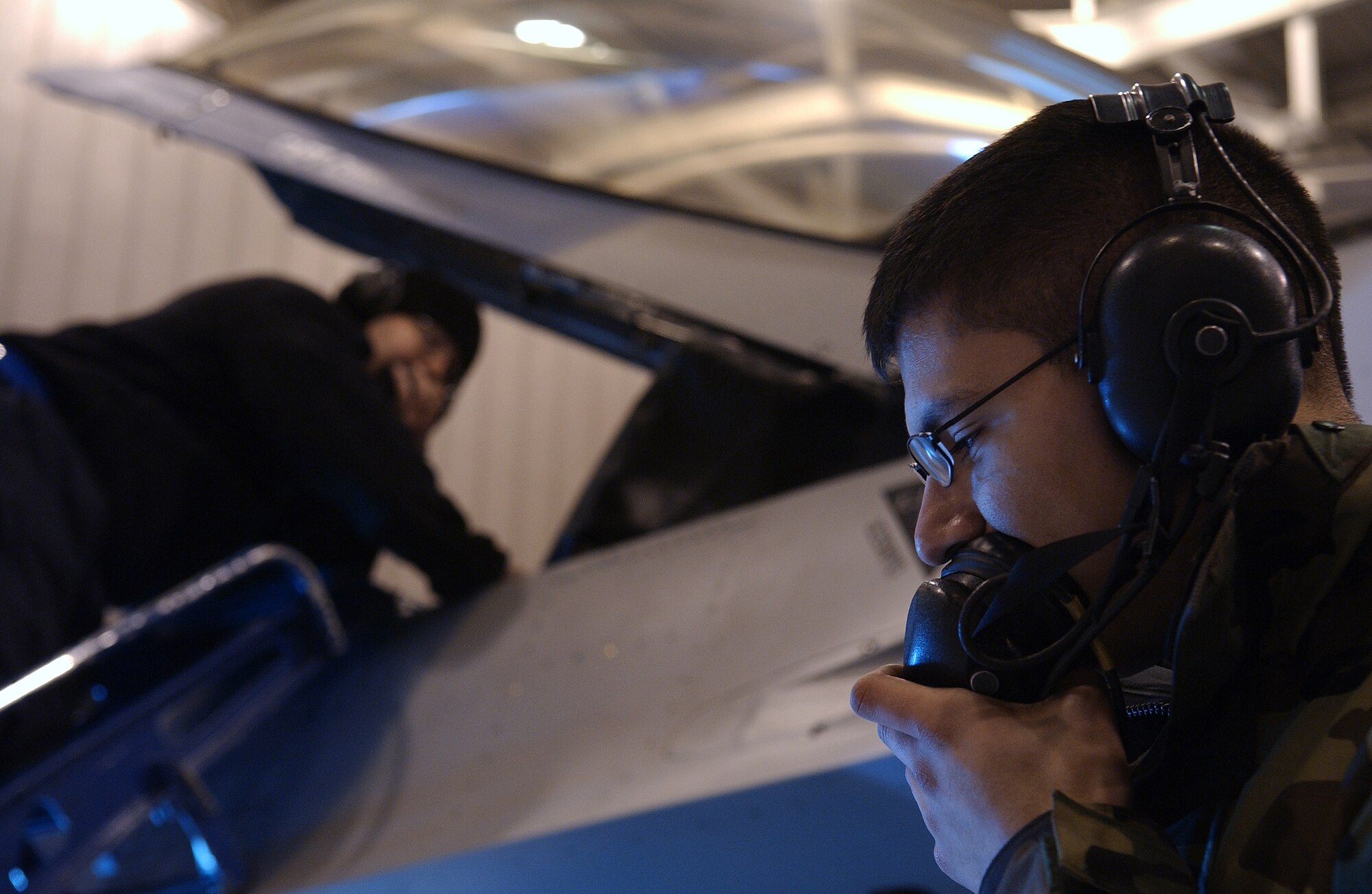 Airman Christian Luna, front, and Senior Airman Jason Menard, back, test out a head set connected to a communication cord, which enables them to communicate with the pilot during pre-flight inspections April 15, 2008, at Eielson Air Force Base, Alaska. The 354th Aircraft Maintenance Squadron is responsible for maintaining the F-16 Aggressors of the 18th Aggressor Squadron enabling them to be mission ready. Both are crew chiefs assigned to the 354th AMXS. (U.S. Air Force Photo/Airman 1st Class Jonathan Snyder)