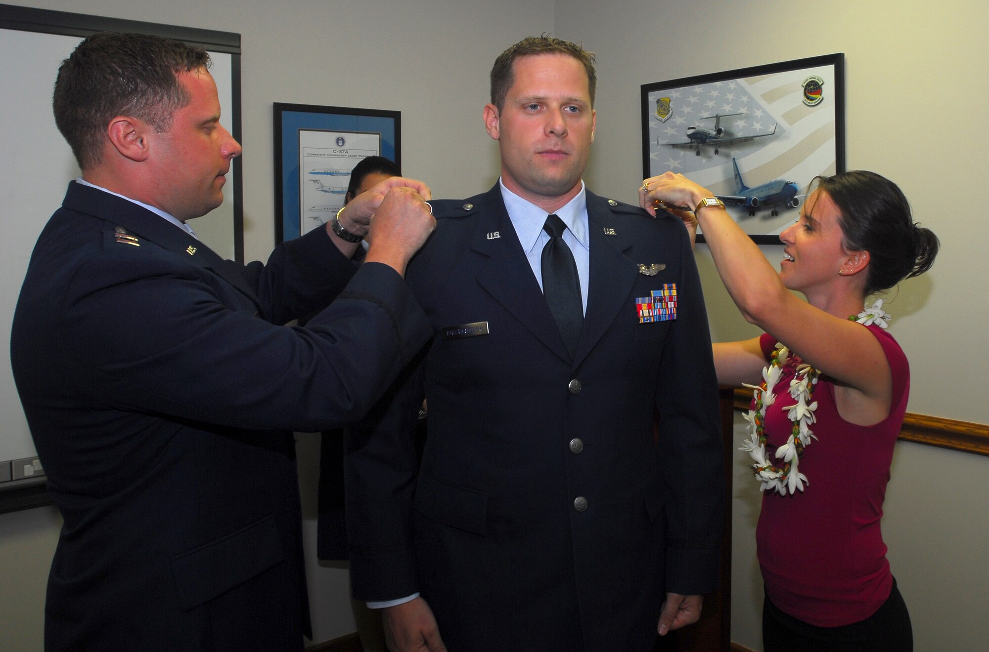 Maj. (sel) Dennis Birchenough (left), Air Force Institute of Technology and Mary Birchenough (right) pin the rank of Major on Peter Birchenough, 65th Airlift Squadron, during a promotion ceremony here. The newly promoted majors are identical twin brothers. U.S. Air Force Photo/Staff Sgt. Erin Smith