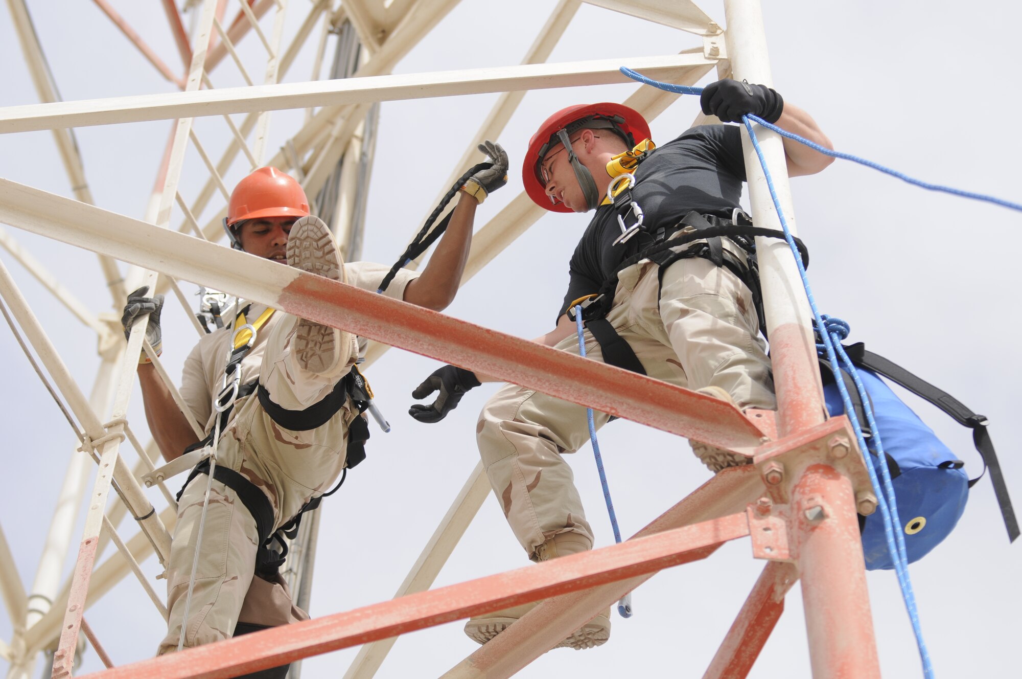 Staff Sgt. Andrew Post, right, helps Staff Sgt. David Reyes secure his safety belt into the communications tower here. 379th Expeditionary Communications Squadron cable and antenna communications system team members must have three secure points of contact before they can start their work. (U.S. Air Force photo/Senior Airman Domonique Simmons)