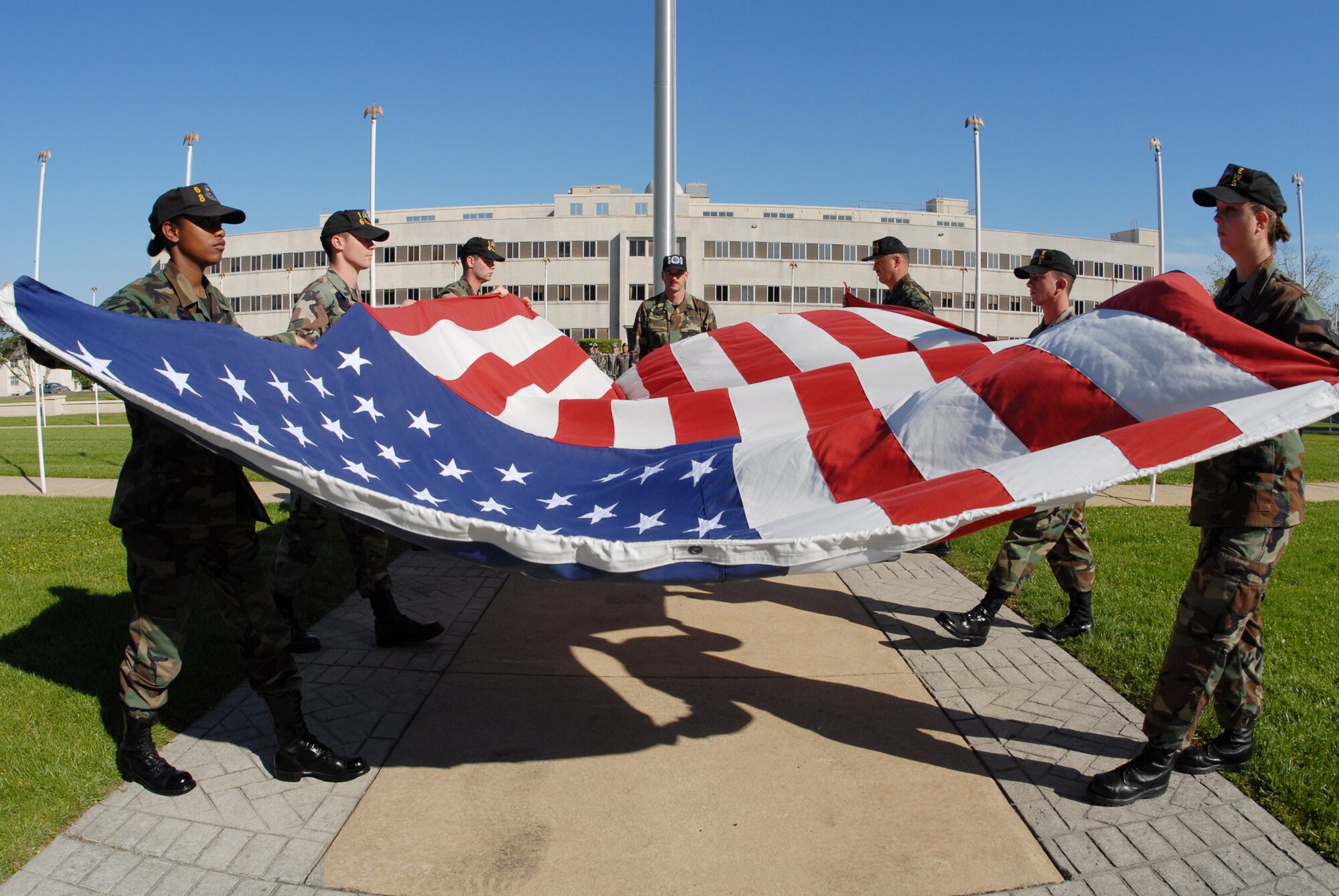 A 53d Electronic Warfare Group flag detail team begins making the first fold of the base flag during the retreat ceremony April 17 at Eglin Air Force Base.  The ceremony was performed solely by the 53d EWG, which had three flights representing the three squadrons.  This is the last base retreat ceremony the EWG will perform as part of the 53d Wing.  By October, the group will transition to Air Force Cyber Command.  Photo by Staff Sgt. Samuel King Jr.