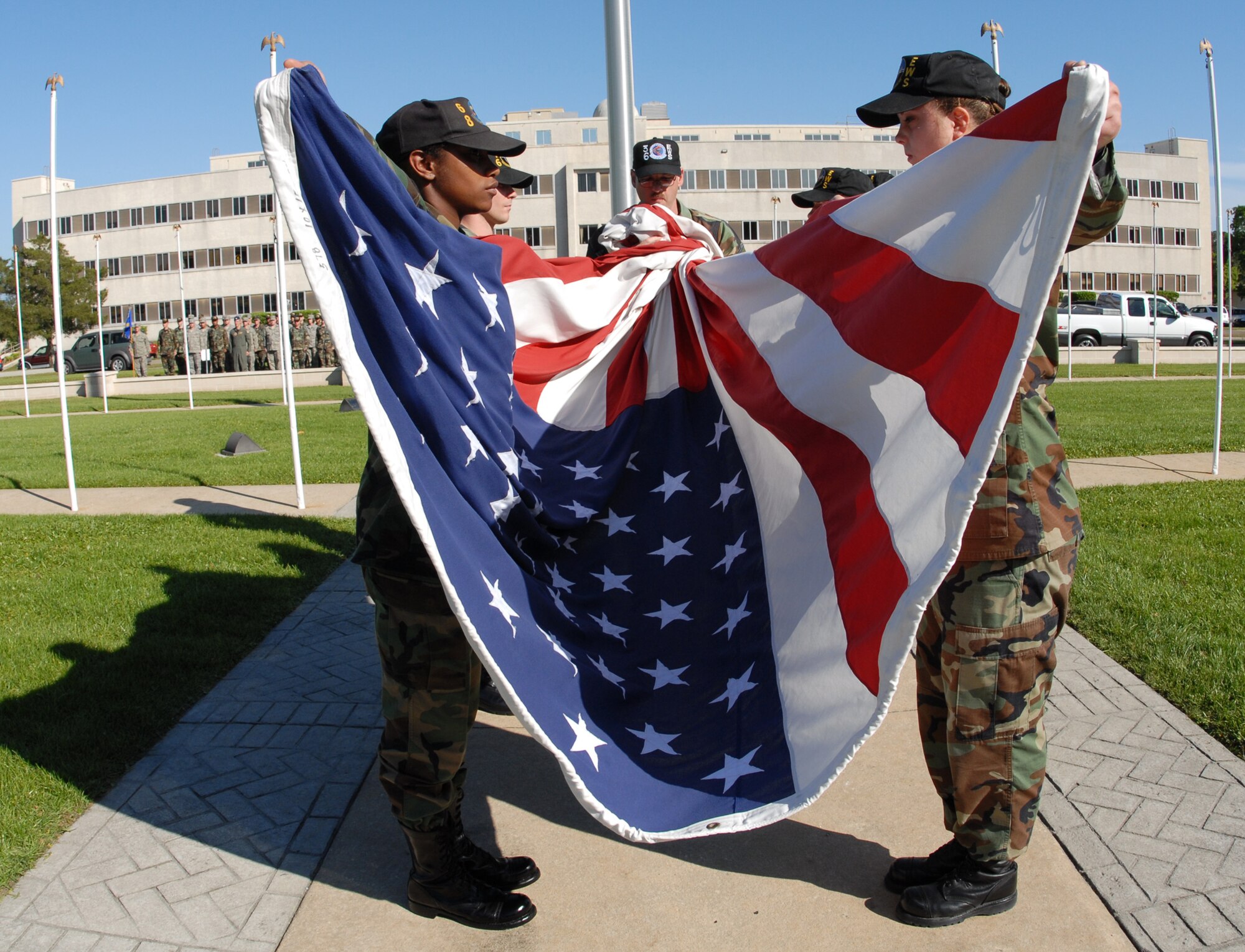 Senior Airman Dietta Morris, 68th Electronic Warfare Squadron, and Staff Sgt. Jacqueline Barker, 16th Electronic Warfare Squadron, hold the flag as it’s unfurled by Master Sgt. Chad Bac, 36th Electronic Warfare Squadron, during the base retreat ceremony April 17 at Eglin Air Force Base.  The ceremony was performed by the 53d Electronic Warfare Group, which had three flights representing the three squadrons.  This is the last base retreat ceremony the EWG will perform as part of the 53d Wing.  By October, the group will transition to Air Force Cyber Command.  Photo by Staff Sgt. Samuel King Jr.