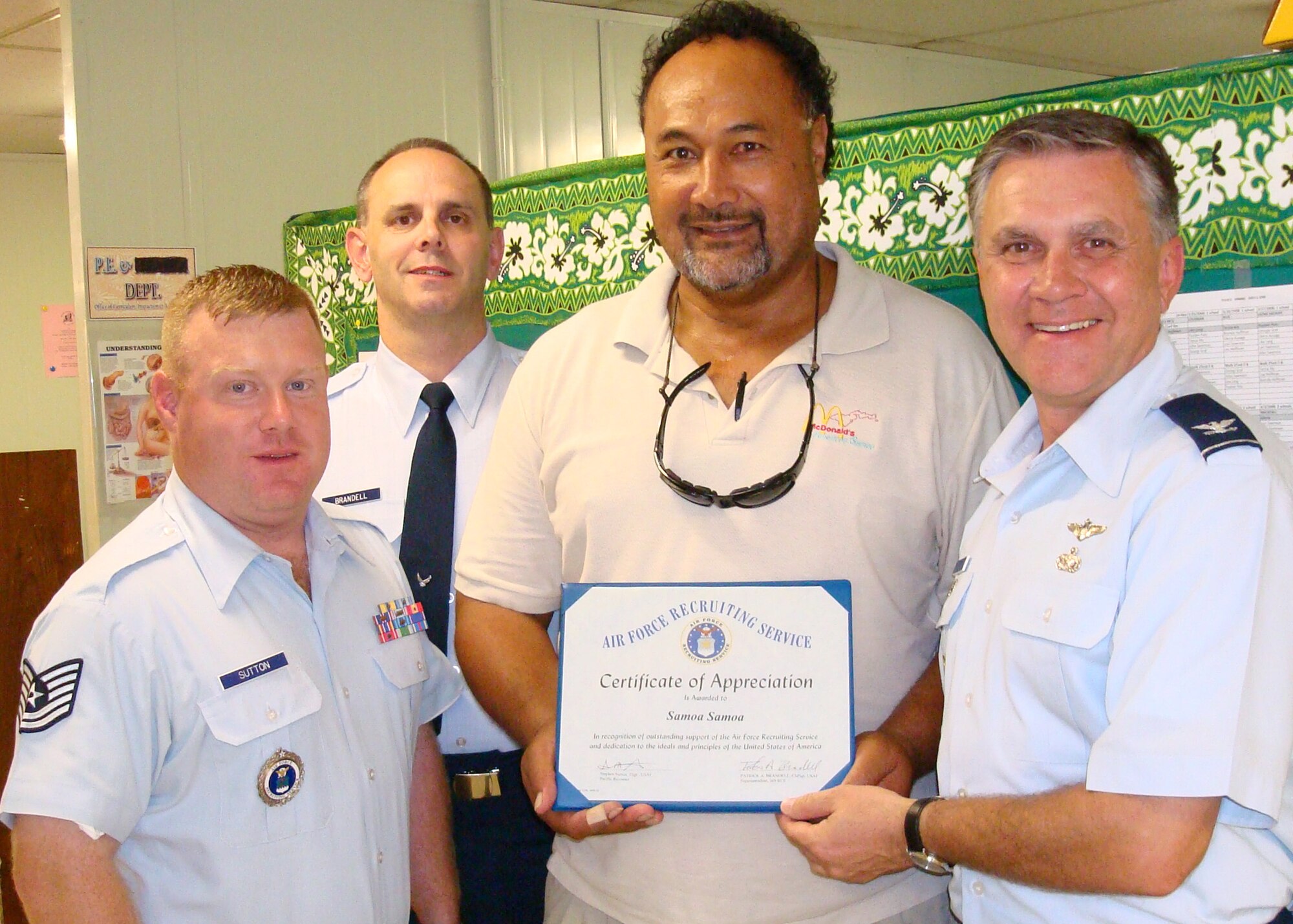 Col. Bill Welch, right, presents former Cincinnati Bengals Running Back Samoa Samoa, center, an Air Force Recruiting Service Certificate of Appreciation in American Samoa April 17 for his support of the U.S. military and recruiting efforts. Mr. Samoa is now the South Pacific island's Government Department of Education athletic director. Colonel Welch is the Air Force Recruiting Service Mobilization Assistant to the Commander. Tech. Sgt. Steven Sutton, far left, 369th Recruiting Squadron recruiter for the region, and Chief Master Sgt. Patrick Brandell, 369th RCS superintendent, support the presentation. (U.S. Air Force photo)