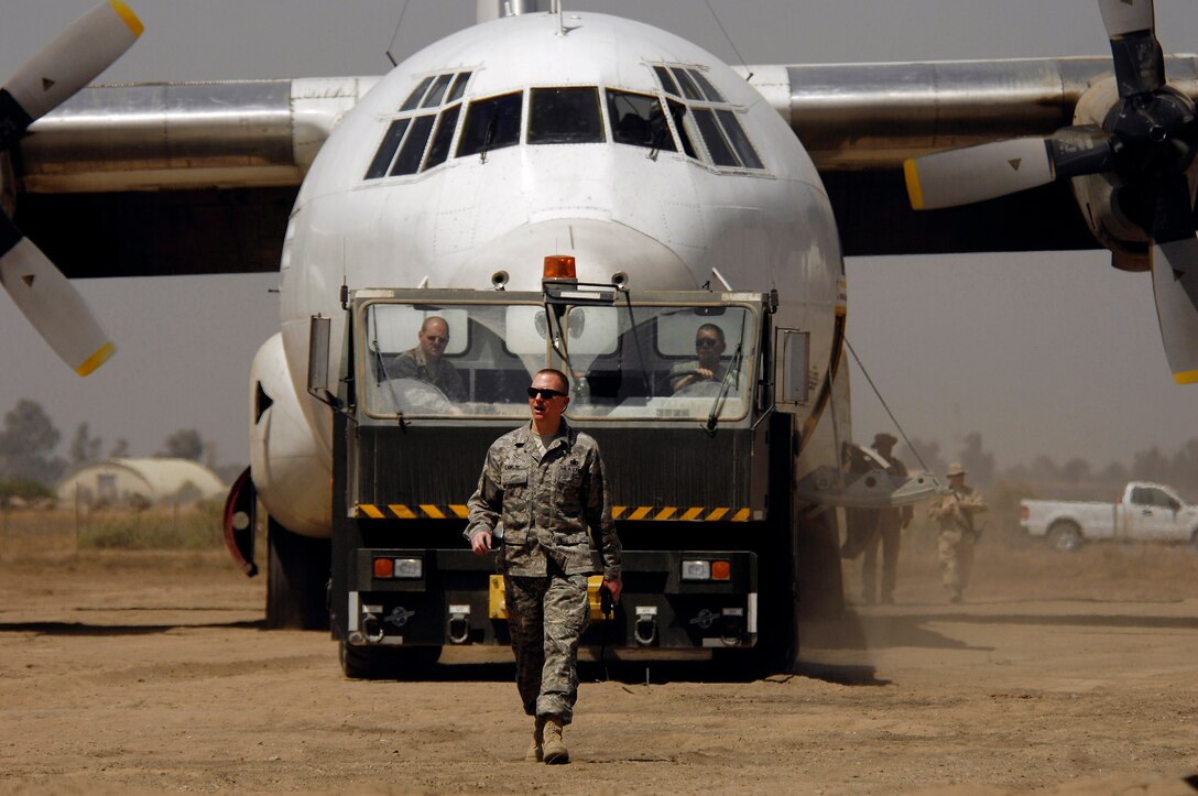 Master Sgt. John Lawlor clears the area as an L-100 aircraft is towed April 1 at Baghdad International Airport. The aircraft rolled past the runway, and Airmen from Sather Air Base prepared it for towing. Sergeant Lawlor is from the 447th Expeditionary Operations Support Squadron. (U.S. Air Force photo/Tech. Sgt. Jeffrey Allen)
