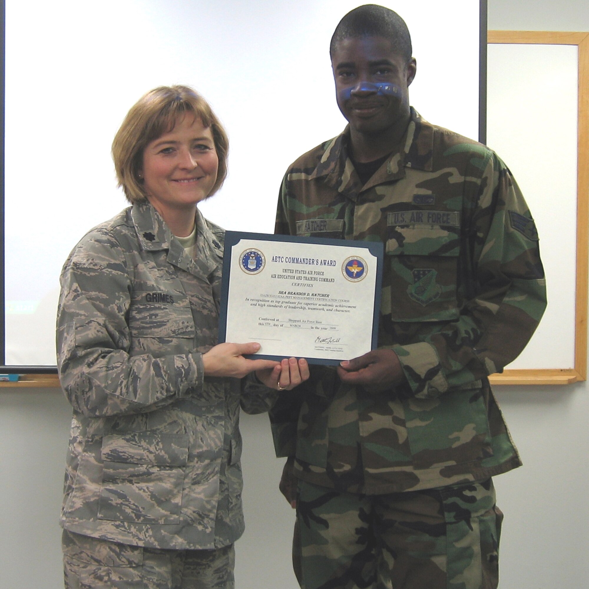 SEYMOUR JOHNSON AIR FORCE BASE, N.C. -- Senior Airman Brandon Hatcher (right), is awarded the Air Education and Training Command Commander's Award for academic achievement. Presenting the award is his commander, Lt. Col. Kerri Grimes. Airman Hatcher is a pest management technician with the 916th Civil Engineer Squadron. 