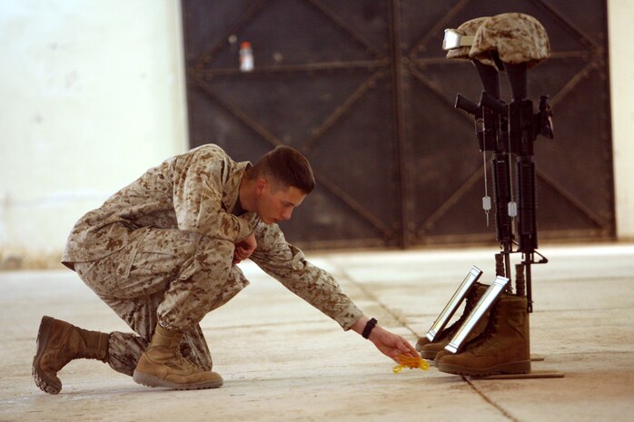 Lance Cpl. Michael Shula, a rifleman with Company F, 2nd Battalion, 24th Marine Regiment, Regimental Combat Team 1, places a bead necklace in-between the Soldiers Crosses of Cpl. Richard J. Nelson and Lance Cpl. Dean D. Opicka during a memorial ceremony remembering the Marines Apr. 18.