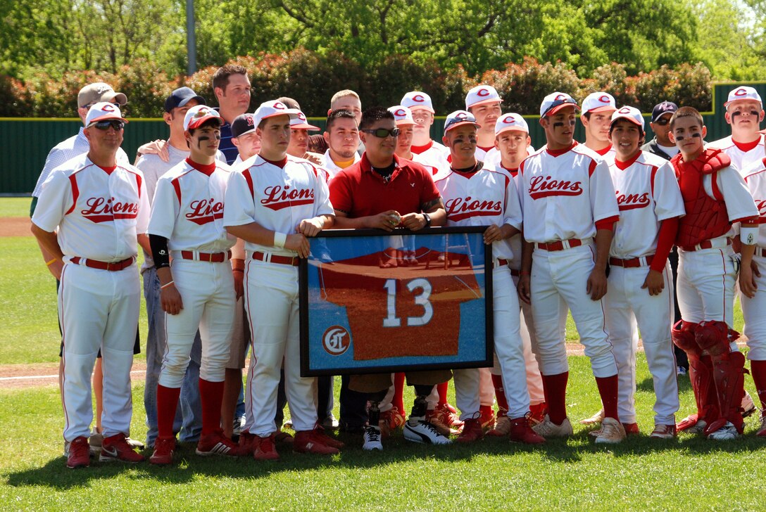 Cpl. Zachary Briseno (center) stands with the current Castleberry Lions baseball team during a pre-game ceremony honoring his sacrifice and service in the Armed Forces. A former Lions player, Briseno suffered injuries in Iraq that resulted in the amputation of both of his legs below the knees. Photo by Sgt. Joel A. Chaverri