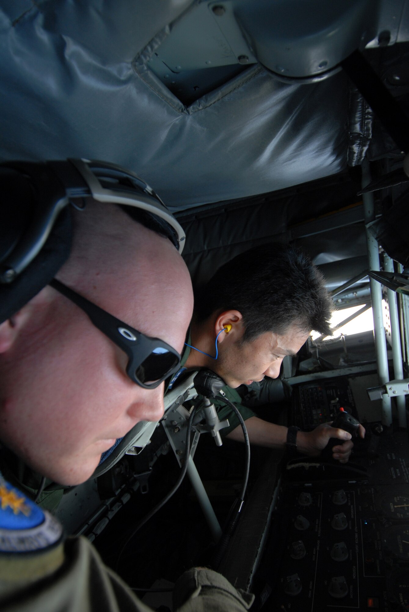 Senior Airman Christopher Pedersen, 909th Air Refueling Squadron, explains to Shinichi Kudoh, Japan Air Self Defense Force, the procedures for operating the boom during refueling training at Kadena Air Base, Japan. The training was conducted to familiarize JASDF members with U.S. Air Force refueling procedures. (U.S.photo/Staff Sergeant Darnell T. Cannady)