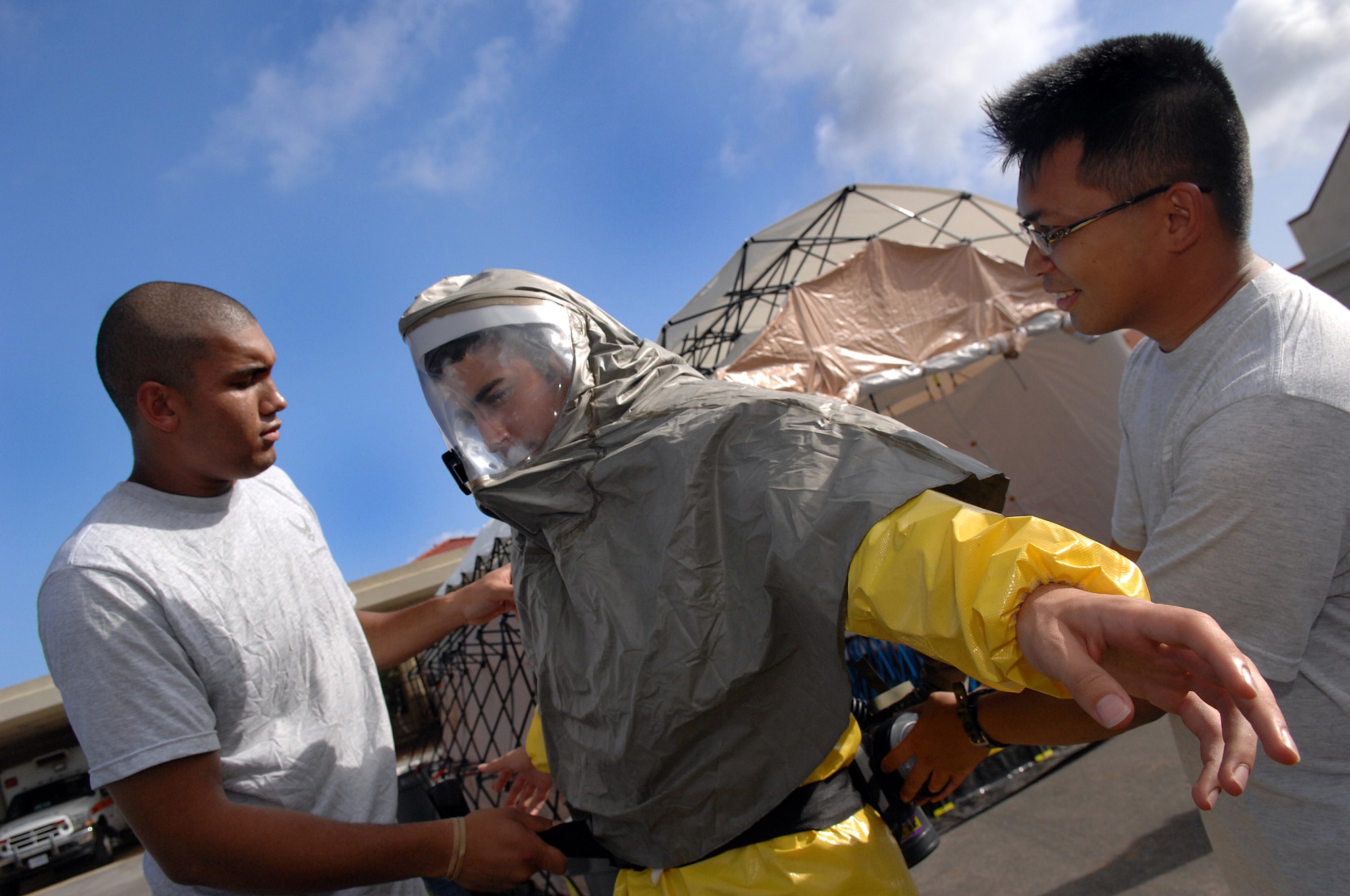 ANDERSEN AIR FORCE BASE, Guam - Senior Amn. Gregory Johnson and Staff Sgt. Al Patague assist Amn. Aaron Guiliano, get into his personal protective equipment to use in the new in-place patient decontamination capabilities  during an exercise April 16th at Andersen Air Force Base, Guam. The IPPDC allows medics to decontaminate patients in the field during a chemical or biological attack. All are members of The Andersen Decontamination Team, 36th Medical Group, Andersen AFB, Guam. (U.S. Air Force photo by Staff Sgt. Vanessa Valentine)


