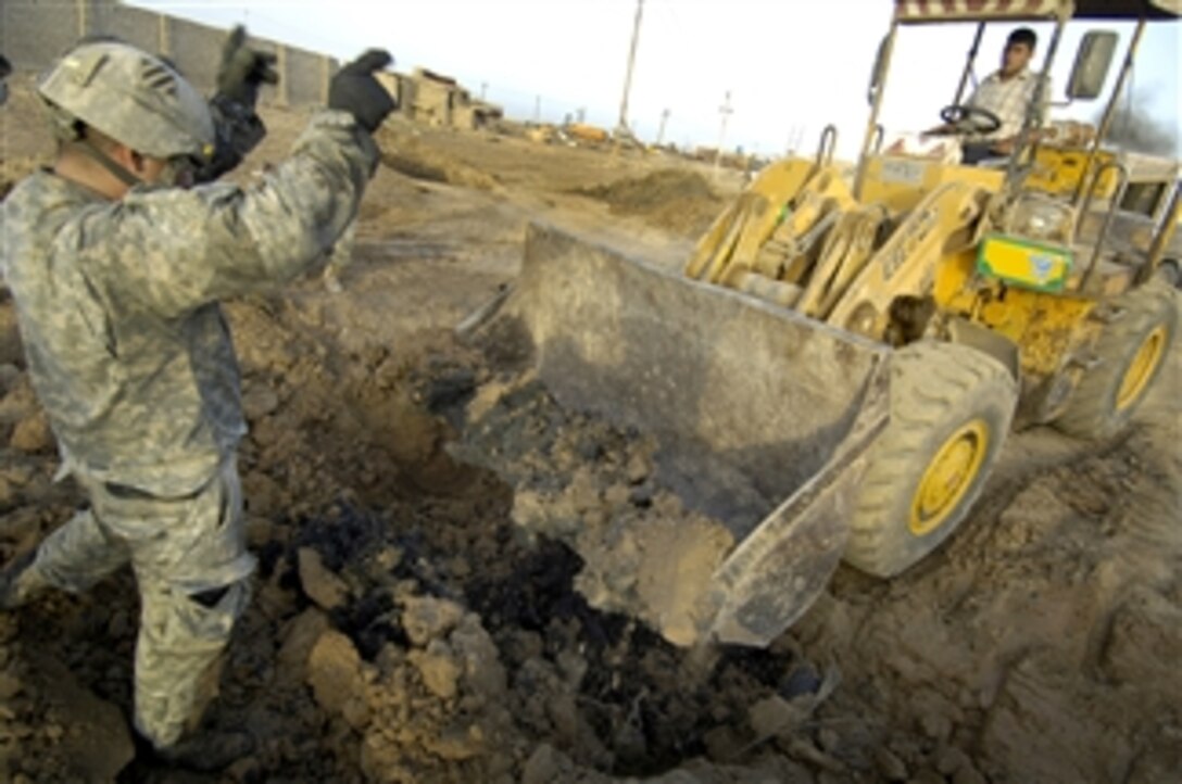 A U.S. Army soldier of the 3rd Infantry Division's Troop C, 3rd Squadron, 1st Cavalry Regiment, 3rd Brigade Combat Team, directs a bulldozer during the excavation of a large weapons cache at a scrap yard in Jabr al-Ansari, Iraq, April 14, 2008. The soldiers discovered the cache following a tip from Sons of Iraq. 