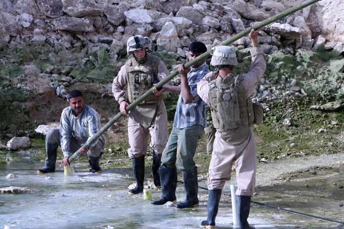 Cpl. Ian A. White, 23, a combat engineer from Birmingham, Ala., and Lance Cpl.  Dustin D. Sauder, 22, a combat engineer from Chattanooga, Tenn., both with Company A, 3rd Combat Engineer Battalion, Regimental Combat Team 5, place four of the 265 Bangalore Torpedoes into pre-drilled holes outside of the Tahadi power plant Sunday with the help of two Iraqi contractors. The engineers blasted through a bed of limestone to aid the Iraqi contractors in creating a cooling pond for the generators. Once completed the power plant should supply power to many more Al Anbar province residents.