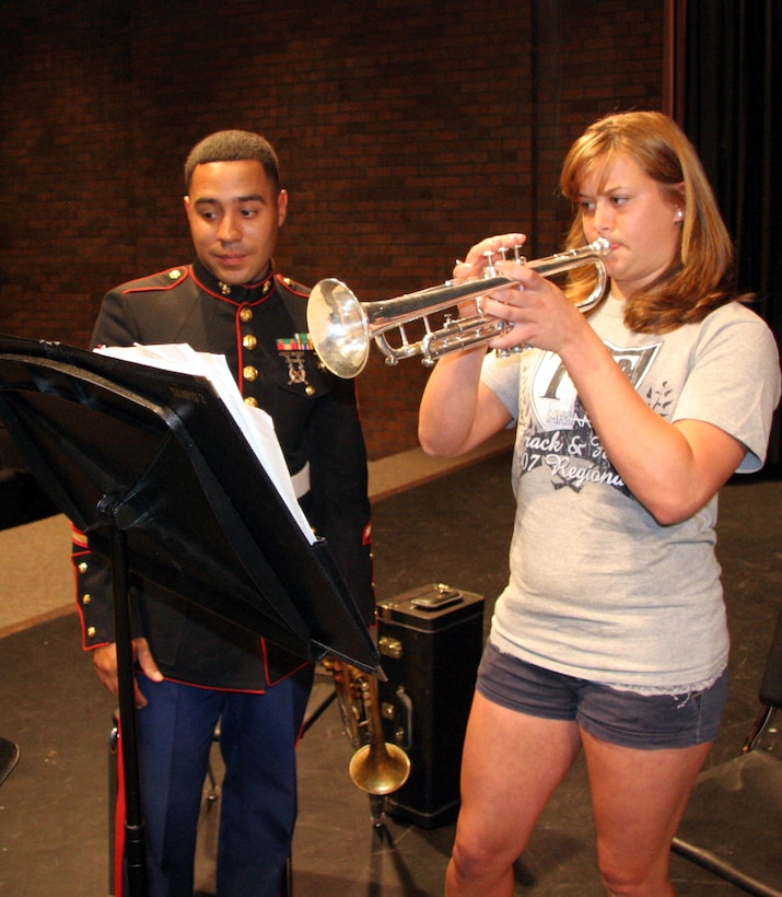 Sgt. Roberto Roman, a trumpet player with the Marine Corps Air Ground Combat Center Twentynine Palms, Calif., shows Danielle Rosenberg, a student at Thornapple Kellogg High School in Kalamazoo, Mich., how to play a new song during the quintet's performance at the high school April 23. The Quintet went on a five-day tour of Recruiting Station Lansing April 21-25, performing for the public and offering clinics for students.