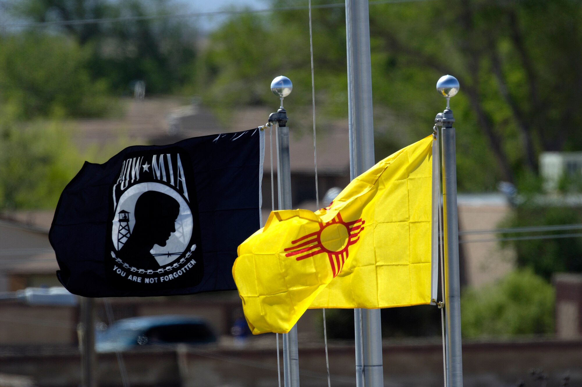 The New Mexico flag and the POW/MIA flags flap in the wind during the Sunset Stealth retirement ceremony at Holloman AFB, N.M., 21 April 2008. The F-117A flew under the flag of the 49th Fighter Wing at Holloman Air Force Base, New Mexico from 1992 to its retirement in 2008. (U.S. Air Force Photo by SSgt Jason Colbert)