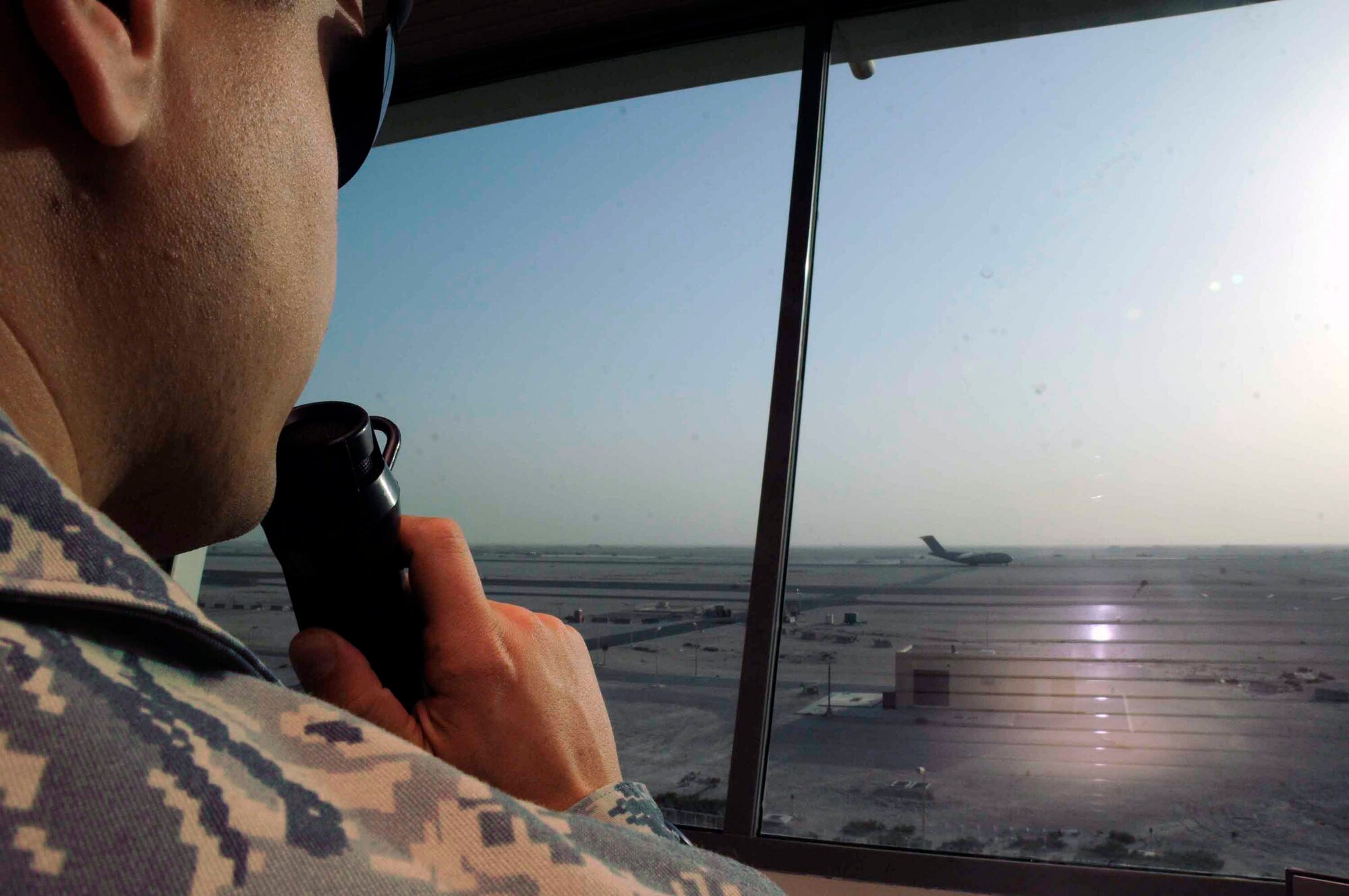 Senior Airman Eric Kindle communicates to aircraft taxiing on the runway through radio channels from the air traffic control tower April 15 at a Southwest Asian air base. Airman Kindle is a 379th Expeditionary Operations Support Squadron air traffic controller journeyman. (U.S. Air Force photo/Senior Airman Domonique Simmons) 
