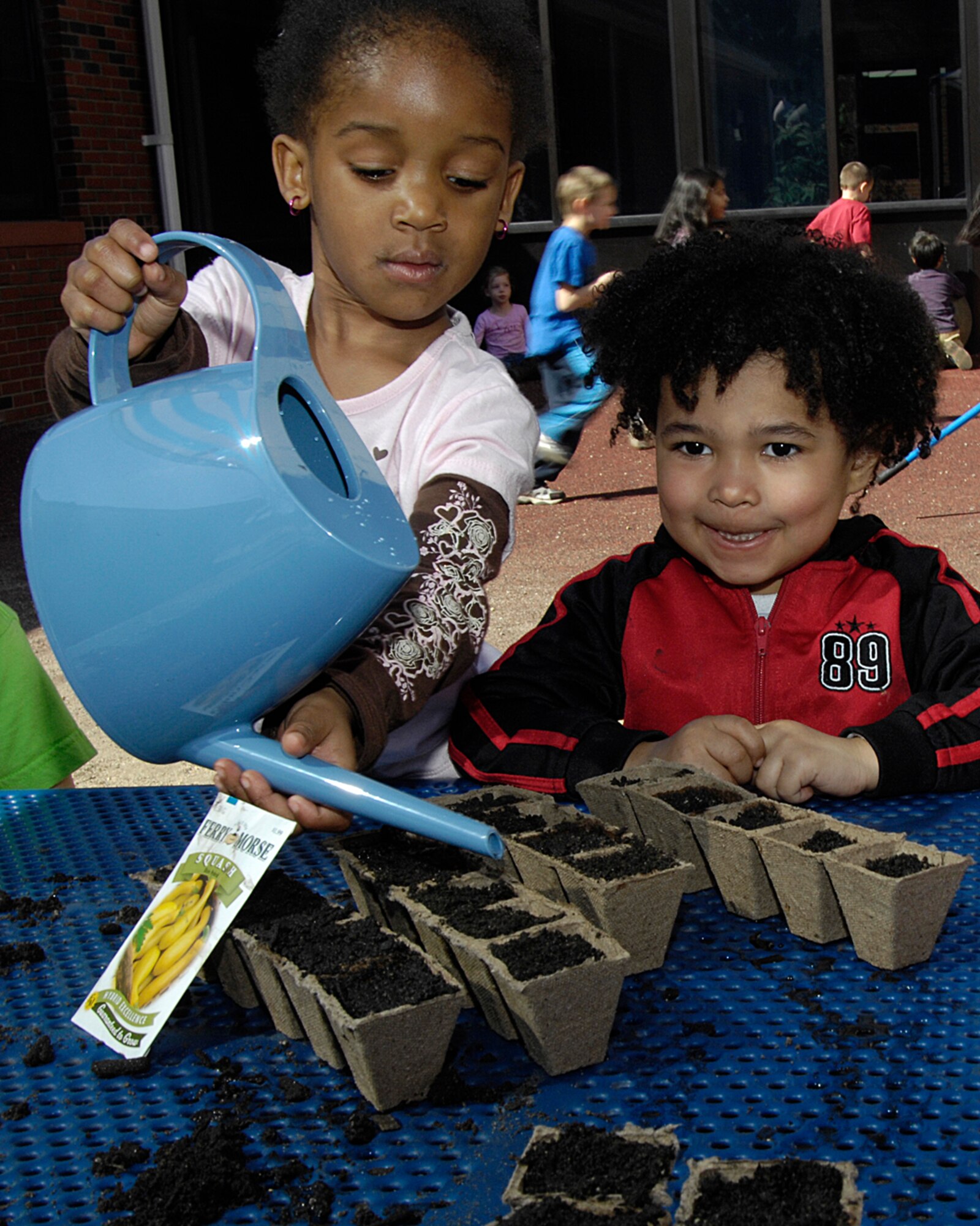 HANSCOM AFB, Mass. – Ronnell Evans (left), waters seeds while Ajani Aztecatl (right) looks on. Children enrolled in the Child Development Center’s Room 5 enjoyed the warmer temperatures April 17 as they planted seeds for their garden as part of the Month of the Military Child activities. (U.S. Air Force photo by Linda LaBonte Britt)

