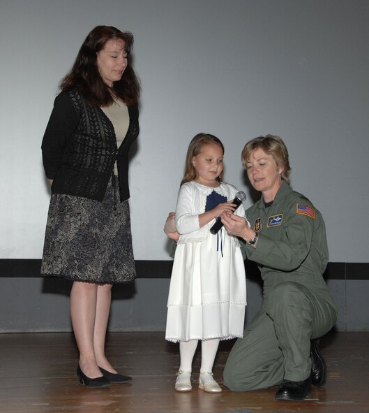 TRAVIS AIR FORCE BASE, Calif. -- Young singer rocks commander’s call: After Ms. Gabrielle Redden, six year old daughter of Master Sgt. Paula Redden from the 349th Operations Group (left), sang the National Anthem during the April B-flight wing commander’s call, the 349th Air Mobility Wing commander, Col. Maryanne Miller (right), got down to Gabrielle’s eye-level to thank her for the wonderful performance. Here, Col. Miller describes to Gabrielle the features of her 349th Wing Commander’s coin, which the Col. presented to her by a traditional handshake. (U.S. Air Force photo Master Sgt. Wendy Weidenhamer)