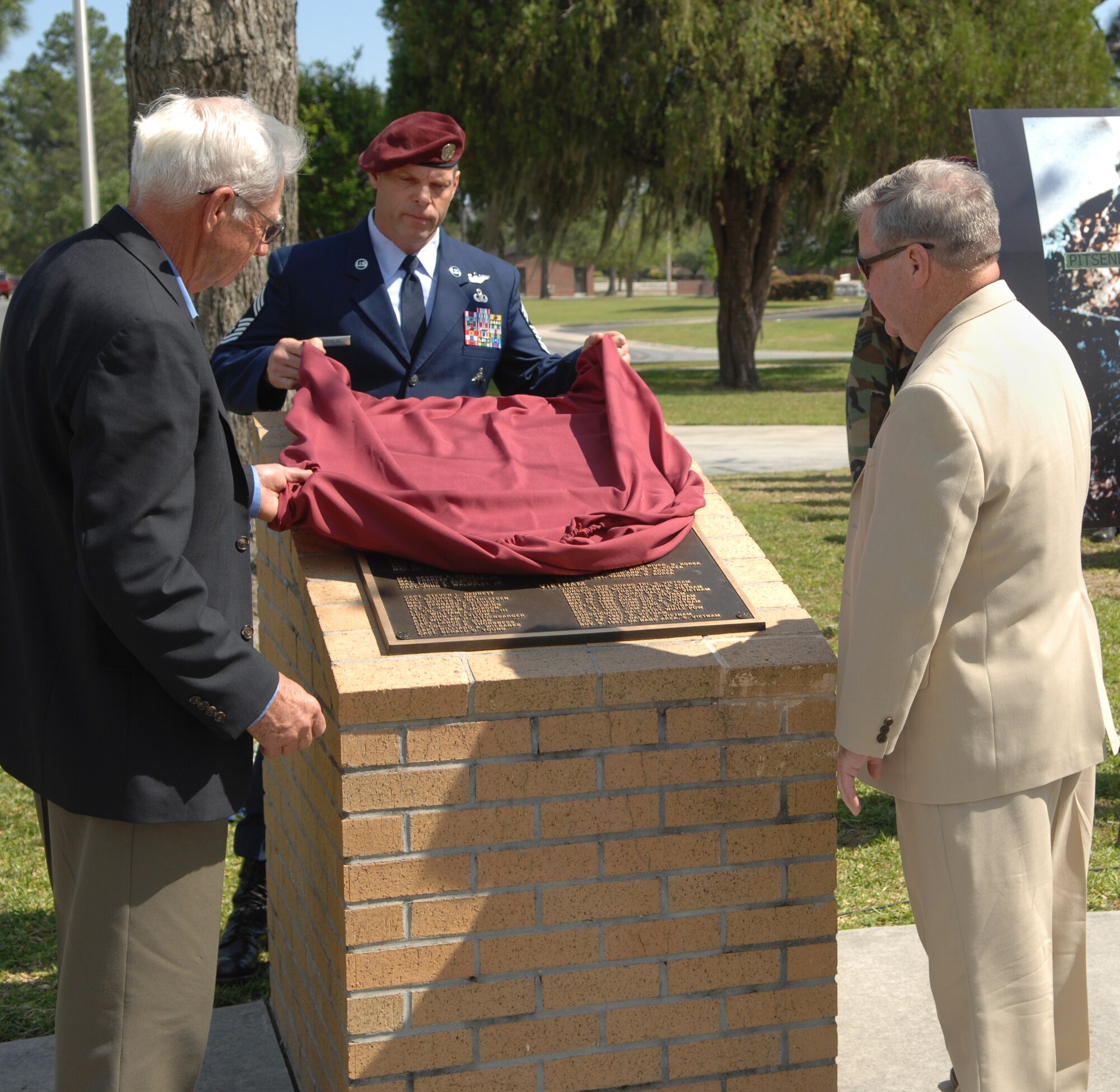 MOODY AIR FORCE BASE, Ga. – Chief Master Sgt. Brian Douglas, 38th Rescue Squadron superintendent, unveils a monument with Chief Master Sgt (Ret) Dave Milster, pararescueman, and Lt. Col. (Ret) Harry Obeirne, dedicated to the men and women in the U.S. Air Force who were recipients of the Medal of Honor here April 18.  Colonel Obeirne participated in the recovery of the body of Airman 1st Class William Pitsenbarger, after his death.  Chief Milster participated in Airman Pitsenbarger’s final mission in Vietnam April 11, 1966. (U.S. Air Force photo by Senior Airman Angelita Lawrence)